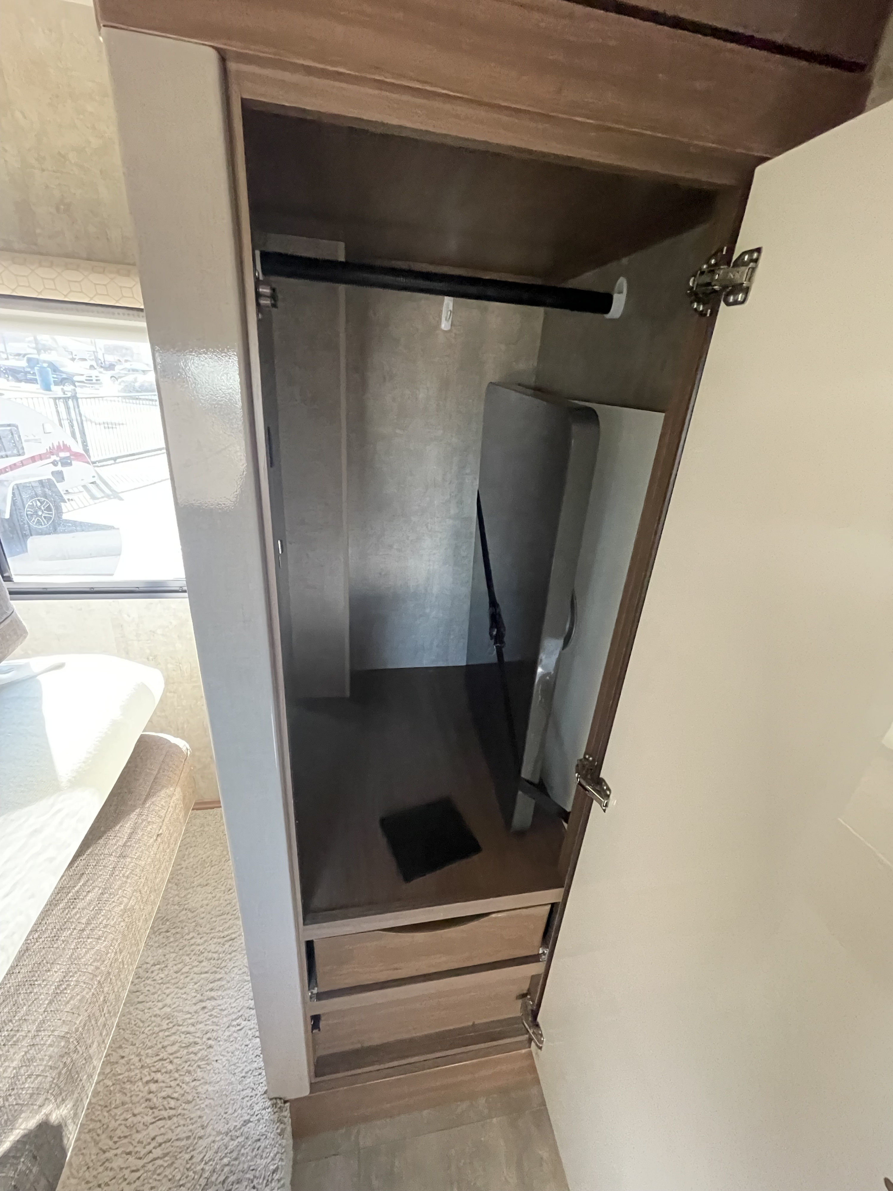 Open RV rental wardrobe with a clothes hanging rod, two drawers, and integrated storage space for essentials.. Winnebago View 2015