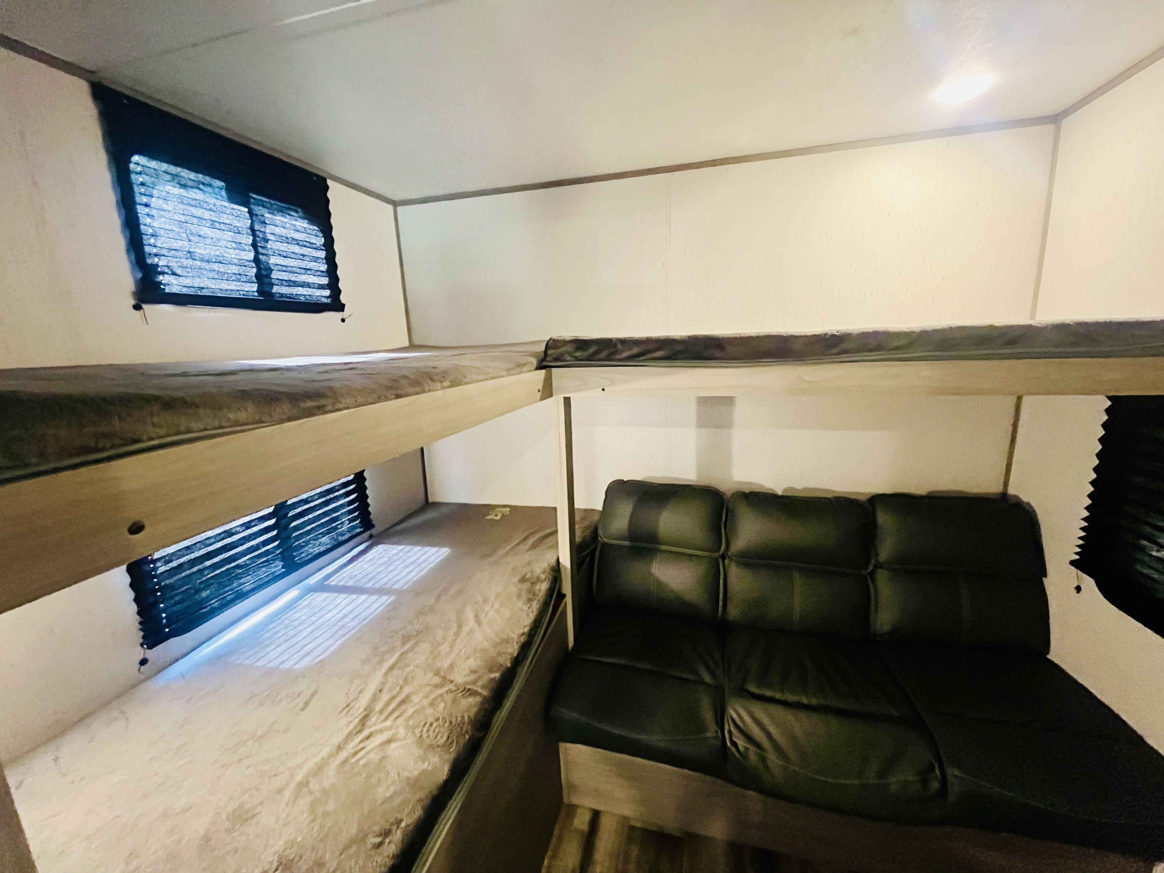 RV rental interior: two bunk beds with window blinds & a comfy dark couch, perfect for travel adventures.. Dutchmen Coleman Lantern 2023
