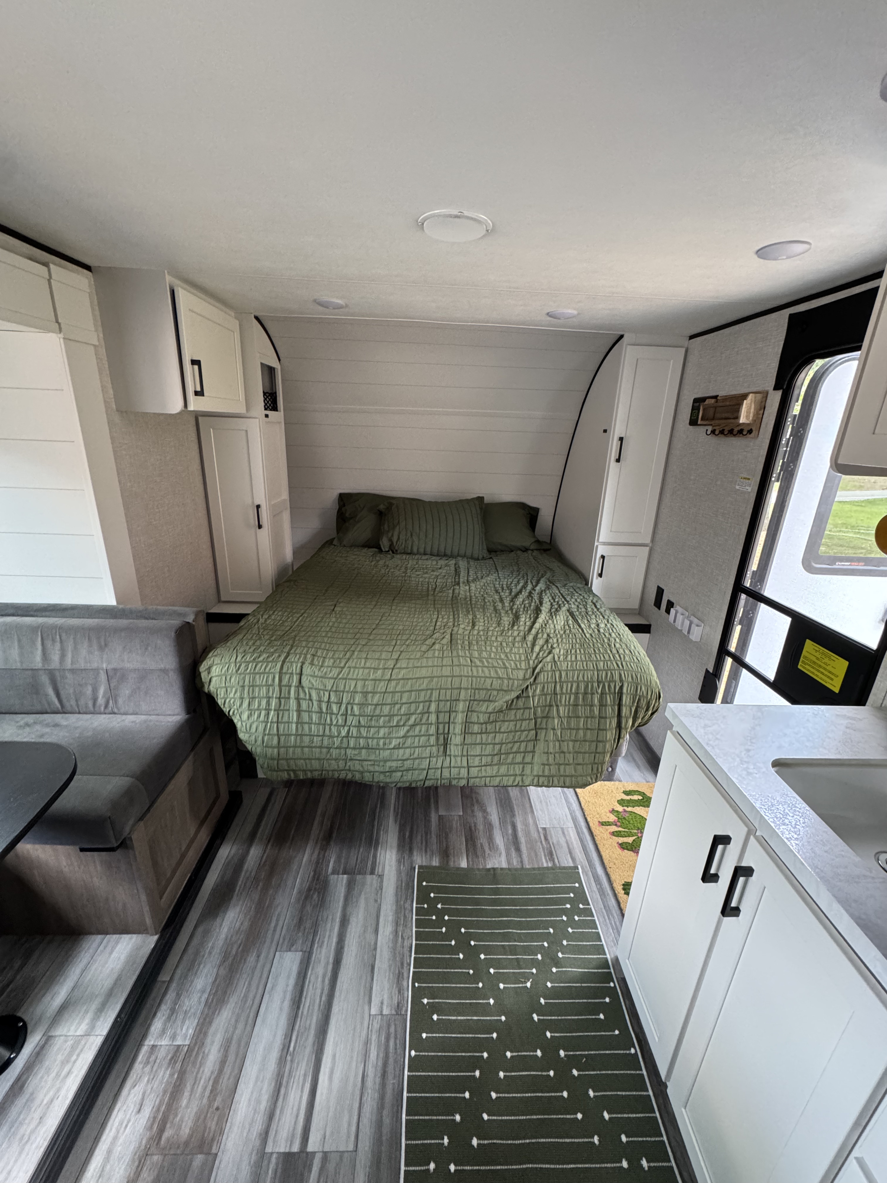 Spacious RV rental interior with a cozy green bed, gray dinette, and white kitchenette, featuring wood-look floors.. Jayco Jay Flight 197MB 2025