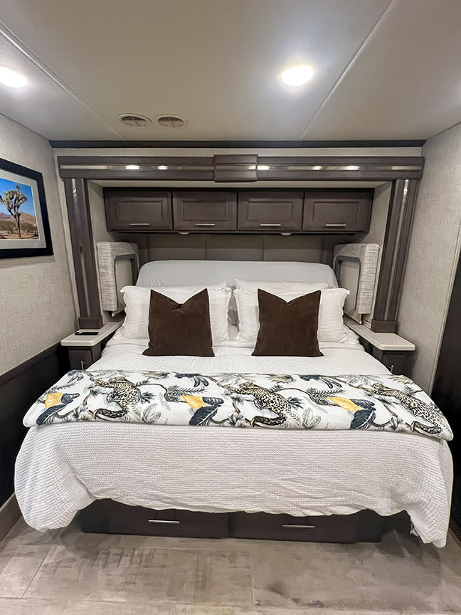 This RV rental's cozy bedroom features a comfortable bed, overhead storage, and stylish decor for your road trip comfort.. Thor Motor Coach 2023
