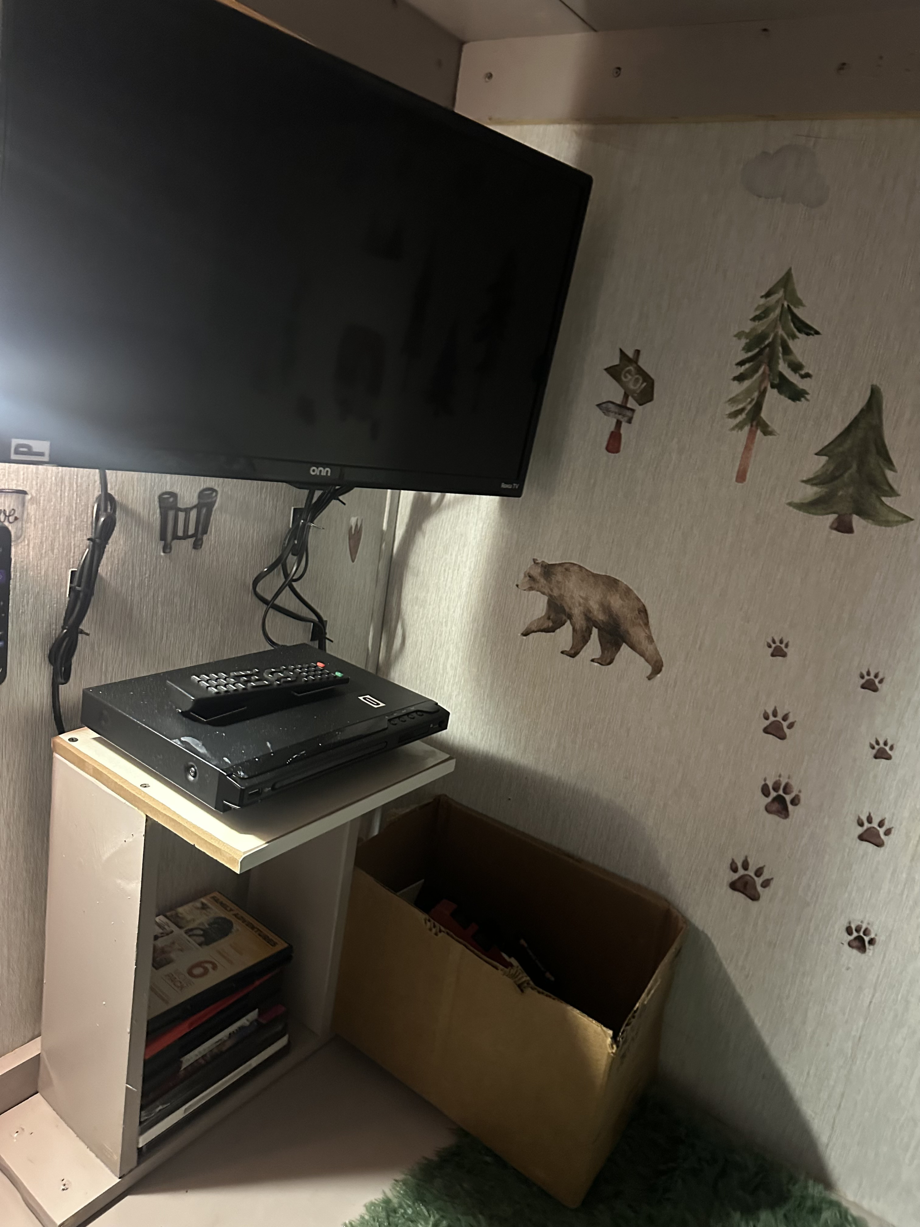 Cozy RV rental entertainment nook featuring a mounted TV, DVD player, and charming bear-themed wall decals.. Forest River Wildwood 2023