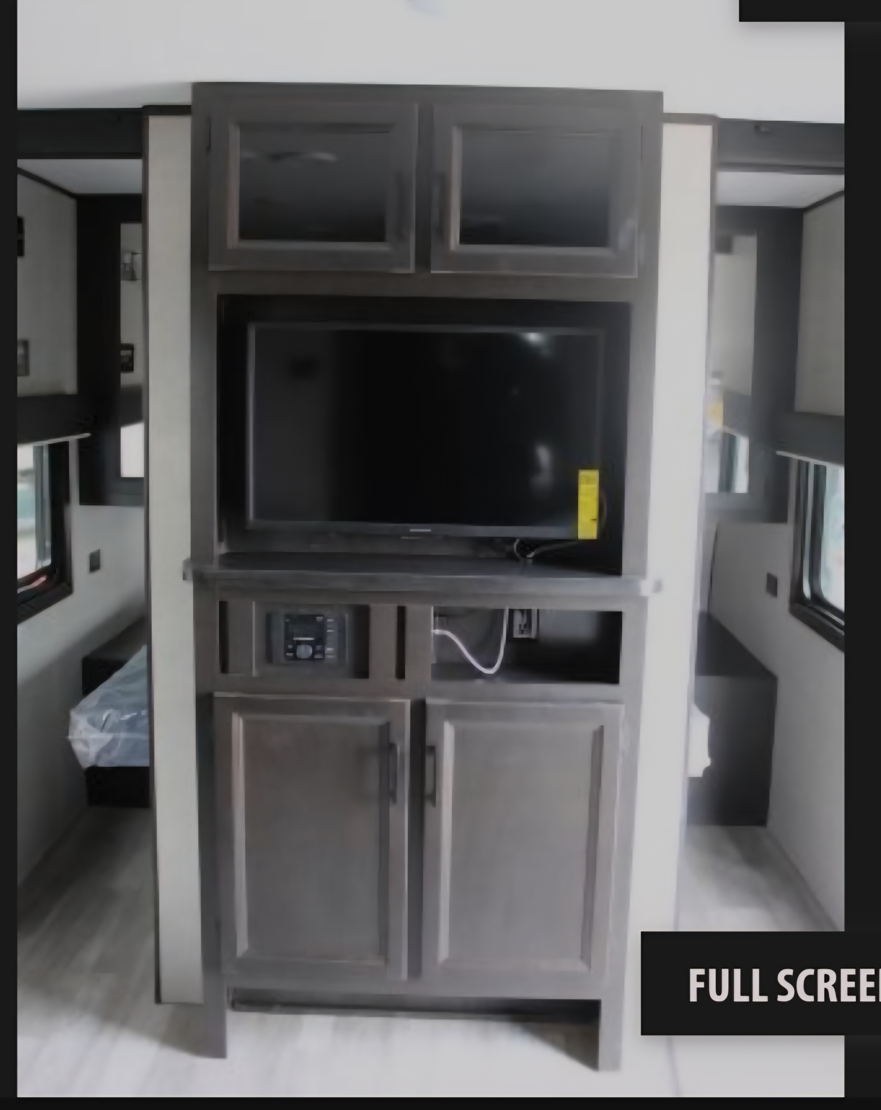 Modern RV rental interior with a central entertainment center, TV, and storage, plus visible sleeping areas featuring beds.. Jayco Jay Flight SLX Rocky Mountain Edition 2022