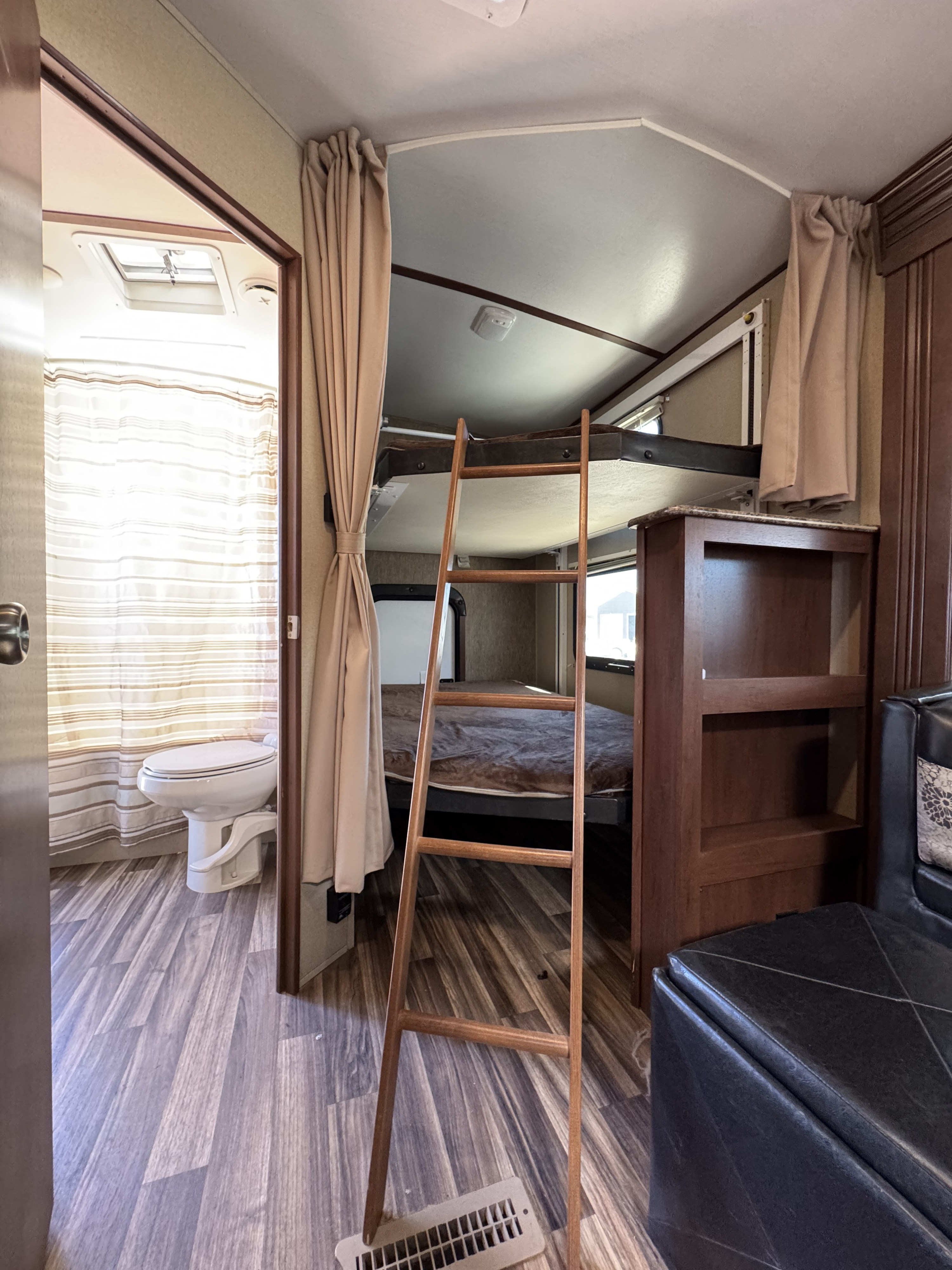 Inside an RV rental: view of the bathroom with toilet, bunk beds with a ladder, and built-in shelving, showing efficient use of space.. Dutchmen Denali Lite Series M-2611BH 2015