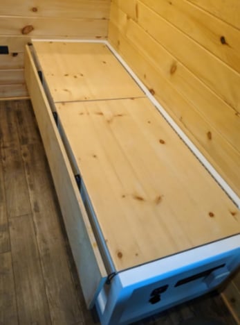 RV rental interior: A wooden bench/bed with lift-up panels for hidden storage. Ideal for space-saving in an RV.. Spring Mercedes 2019