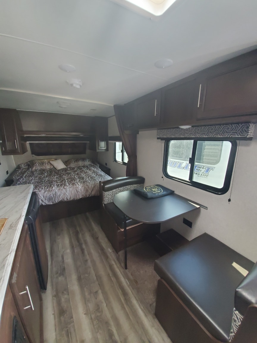 Cozy RV rental interior showcasing a comfortable bed, dinette, and kitchenette, perfect for your next adventure.. Jayco Jay Flight SLX Baja Edition 2019