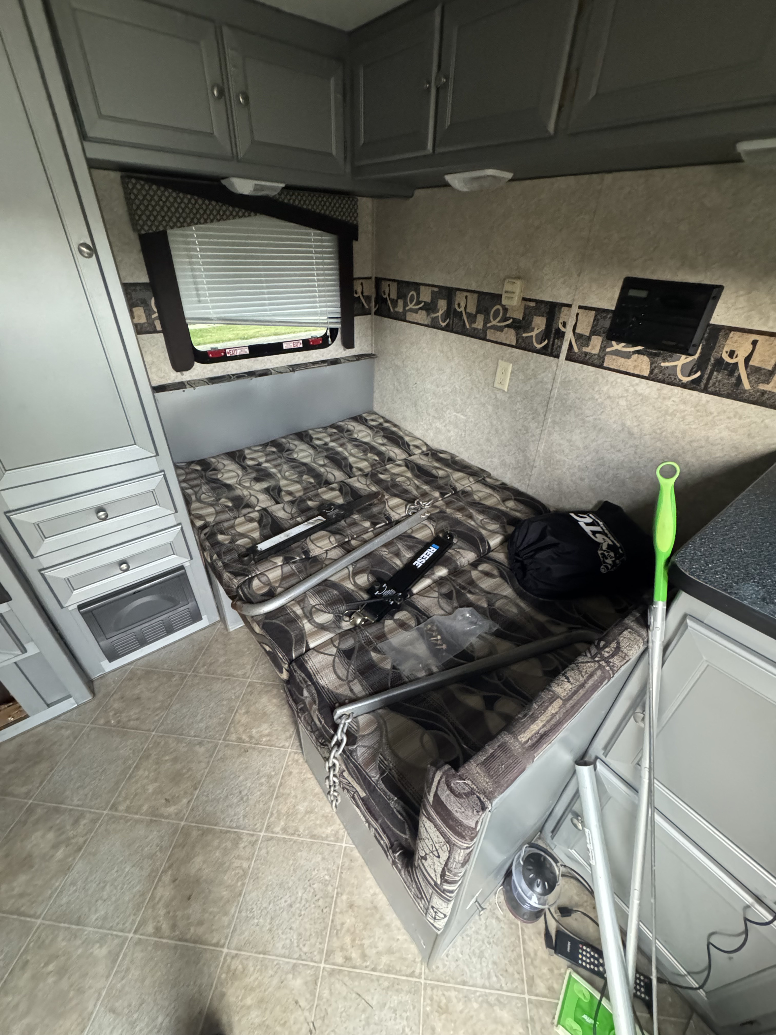 Inside this RV rental: a compact living space featuring a bed, ample storage cabinets, and a window view.. Roadmaster Toy hauler 2007