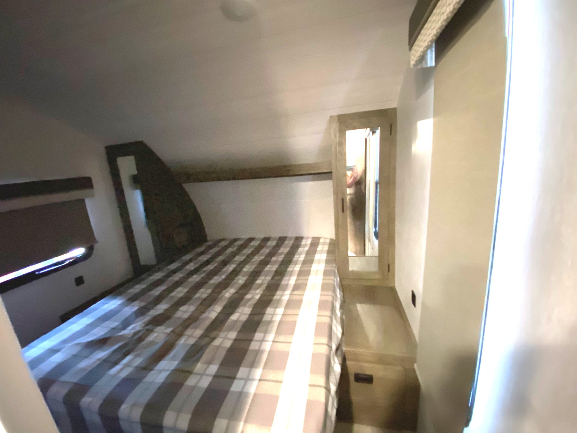 Cozy RV rental bedroom with a plaid bed, window, and mirrored cabinet. Perfect for your next adventure.. Forest River Wildwood 2022