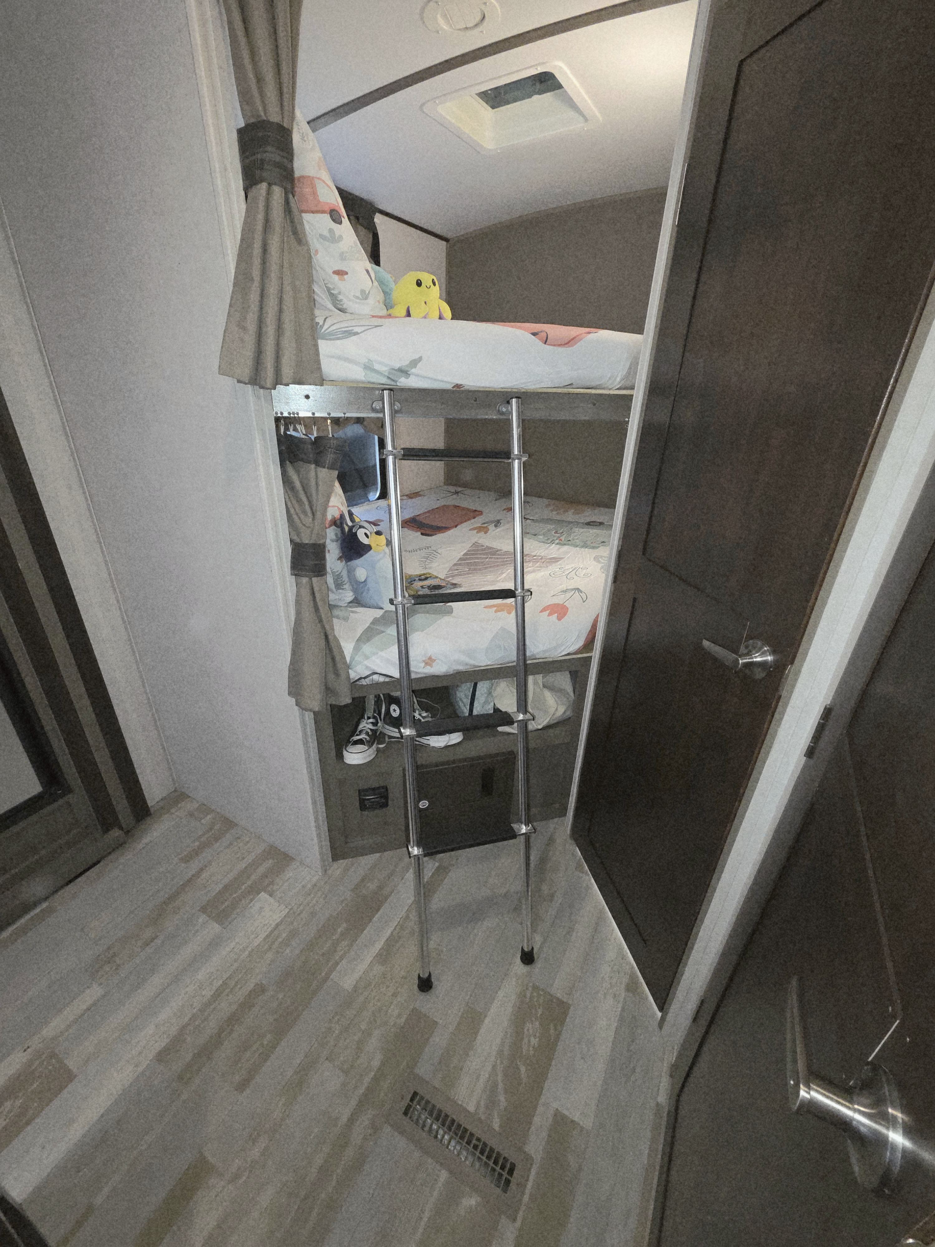 RV rental interior: cozy bunk beds with ladder, perfect for kids. Features a skylight and wood-look flooring.. Forest River Surveyor 2018