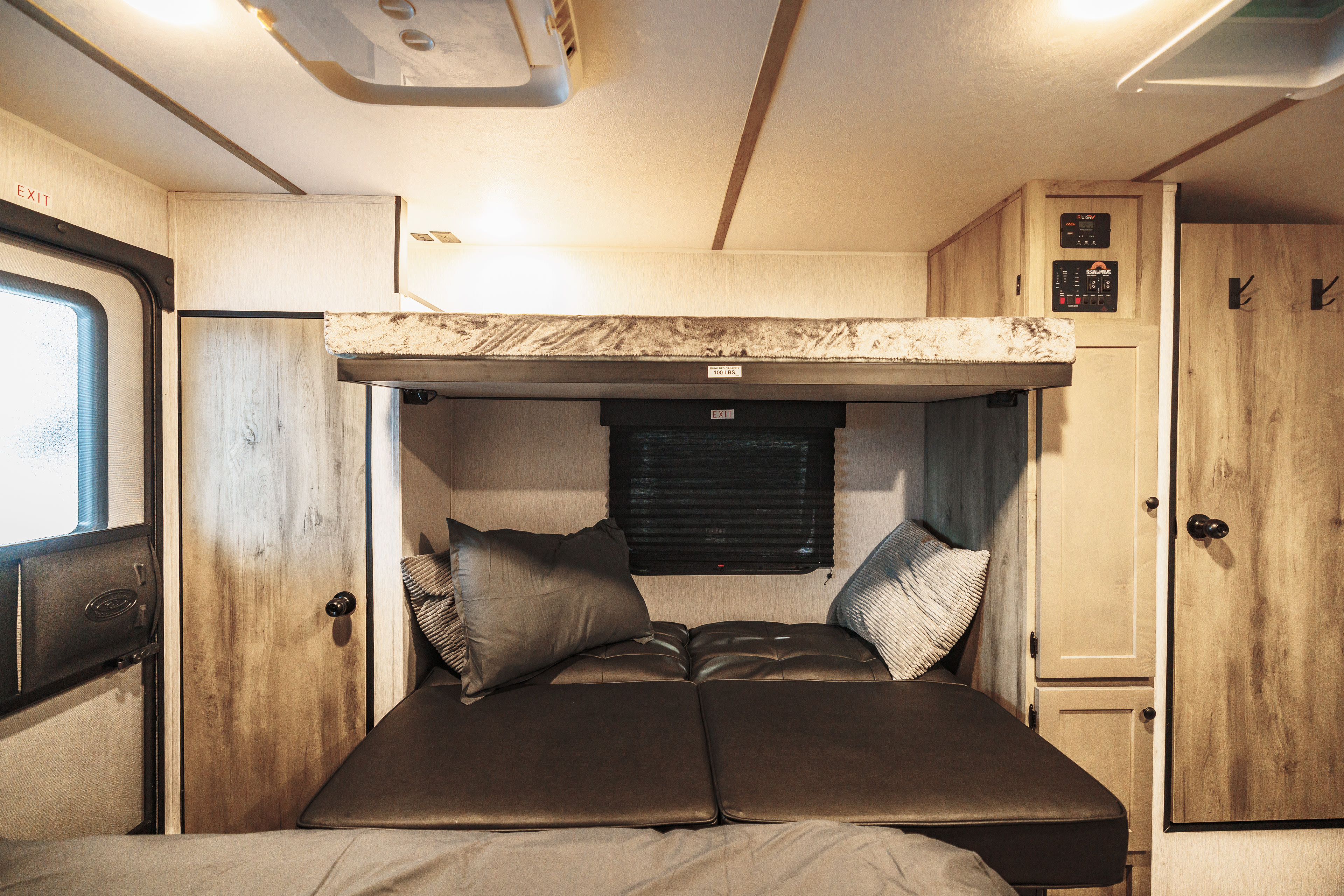 Cozy RV rental interior featuring a lower bed/sofa and an upper bunk bed, ideal for a comfortable stay.. Wayfinder Go Lite 2026