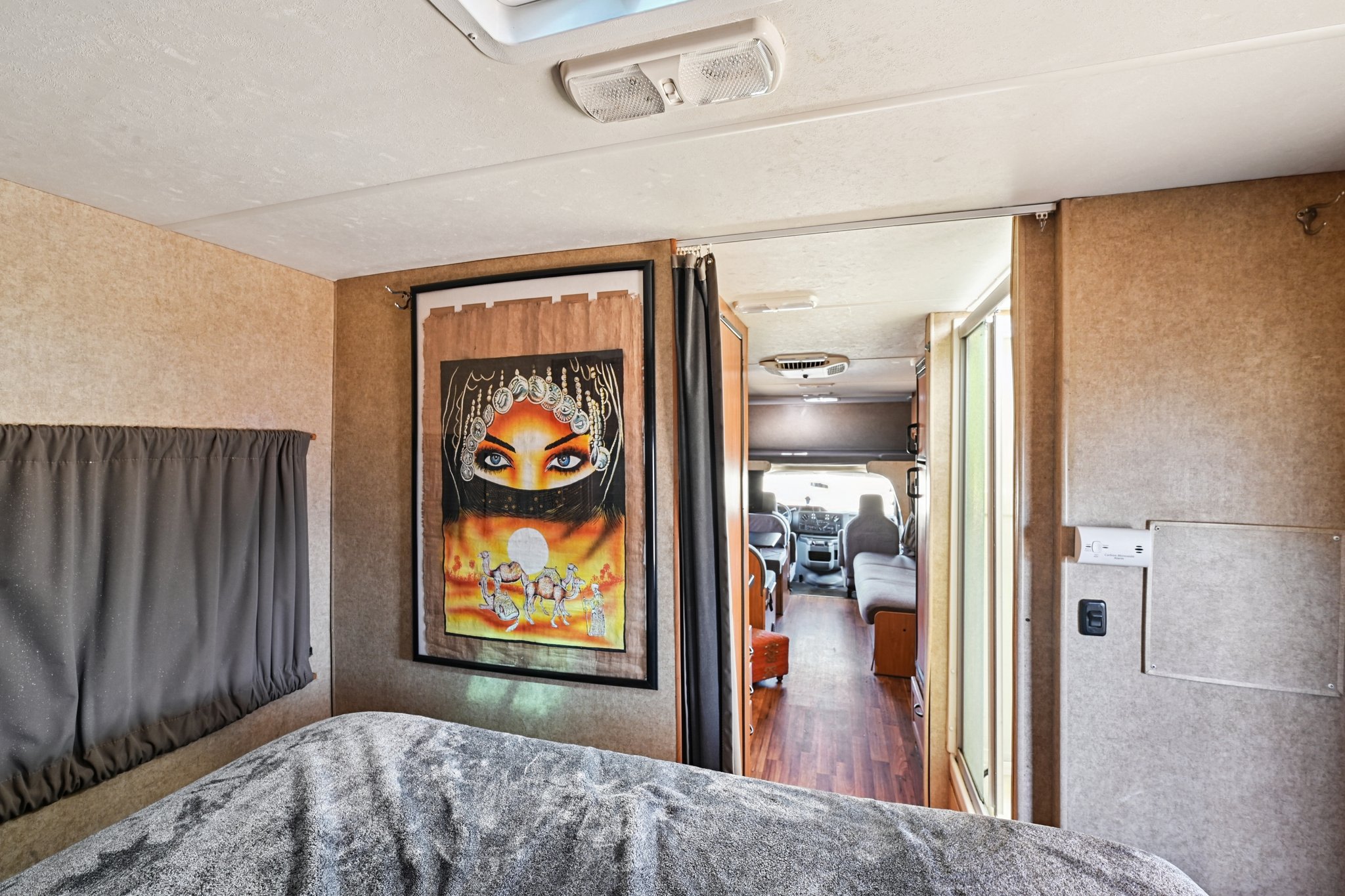Inside an RV rental: a bedroom with unique art, and a hallway leading to the front living/driving areas.. Thor Majestic 2012