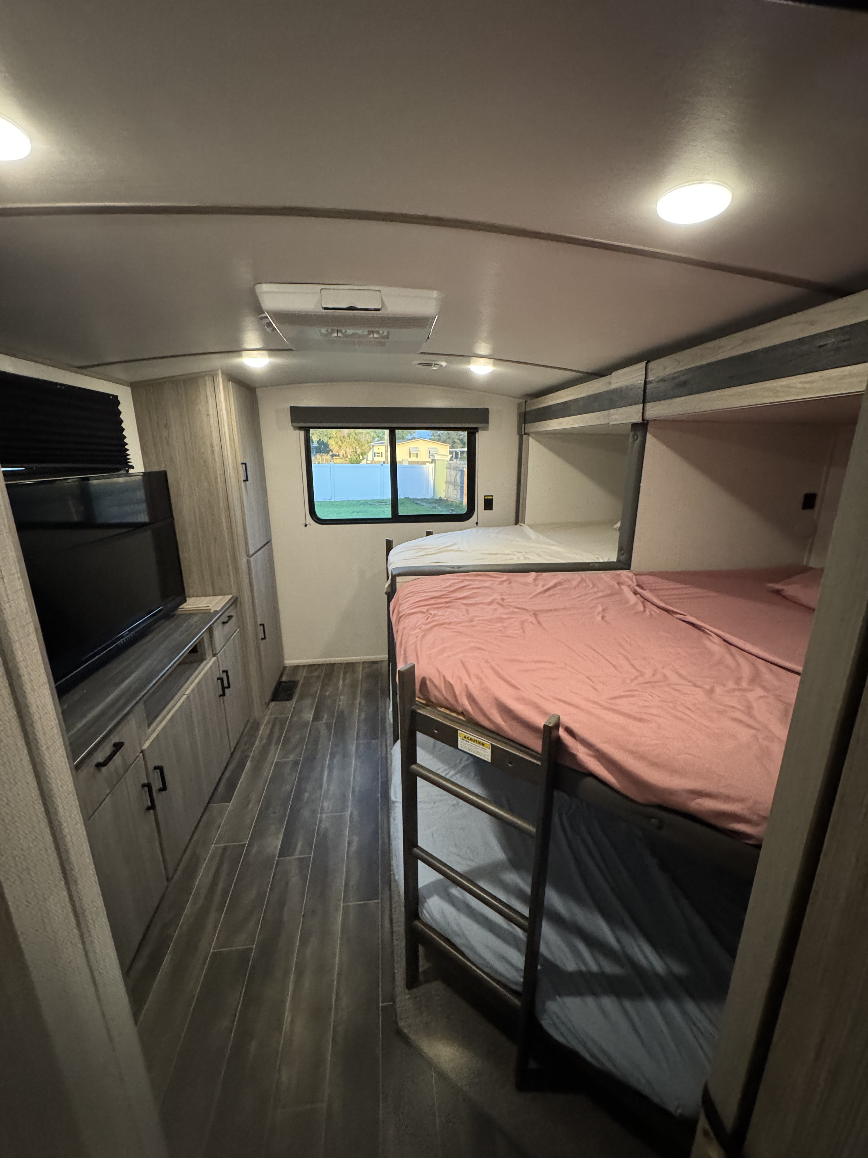 This RV rental interior features cozy bunk beds with a ladder, a TV console, and ample storage, ideal for family trips.. Keystone RV Passport GT Ultra Lite 2023