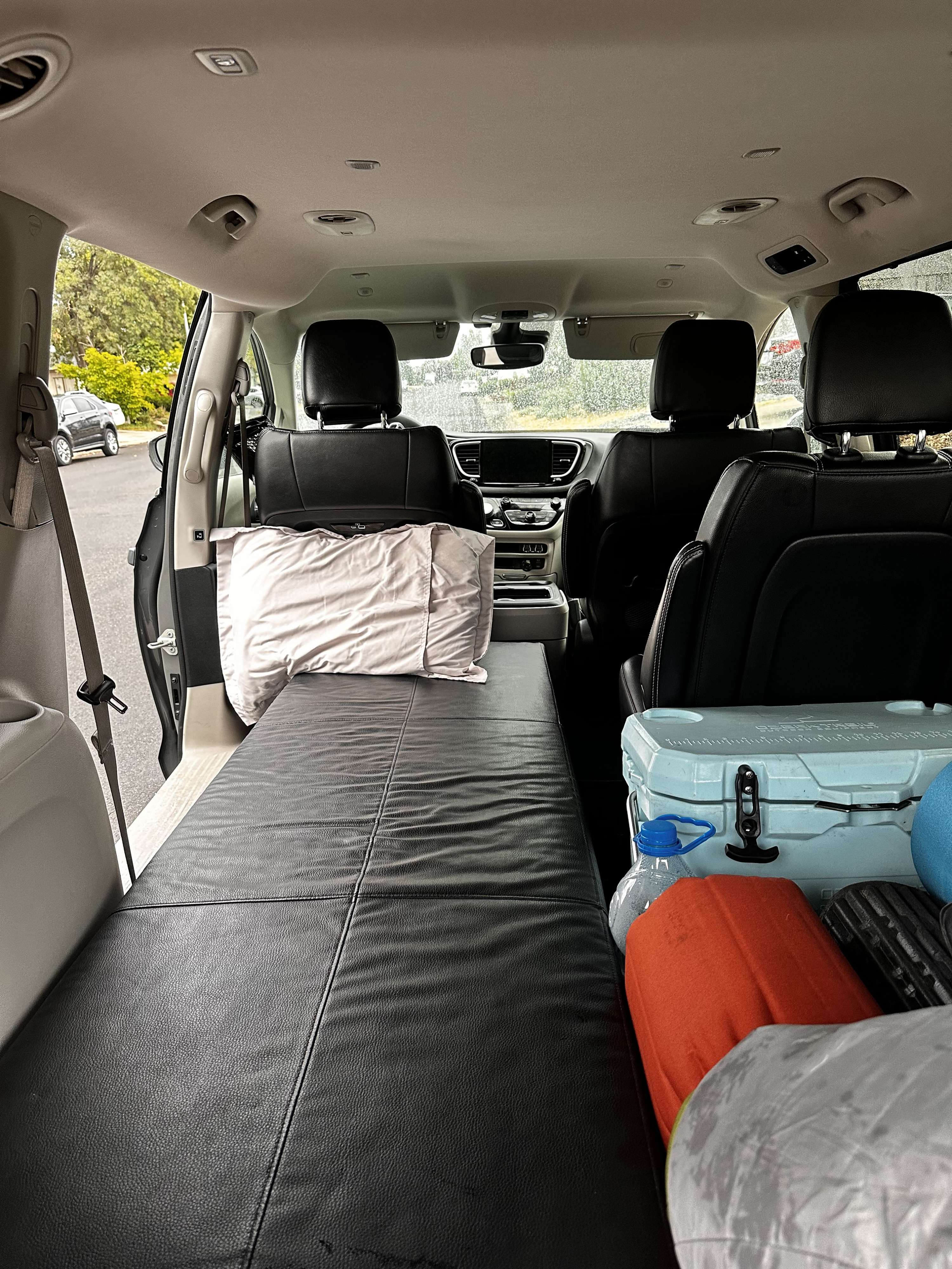 Minivan interior with sleeping platform & pillow, cooler & gear. Ideal for car camping, a road trip, or RV rental alternative.. Chrysler Pacifica 2022