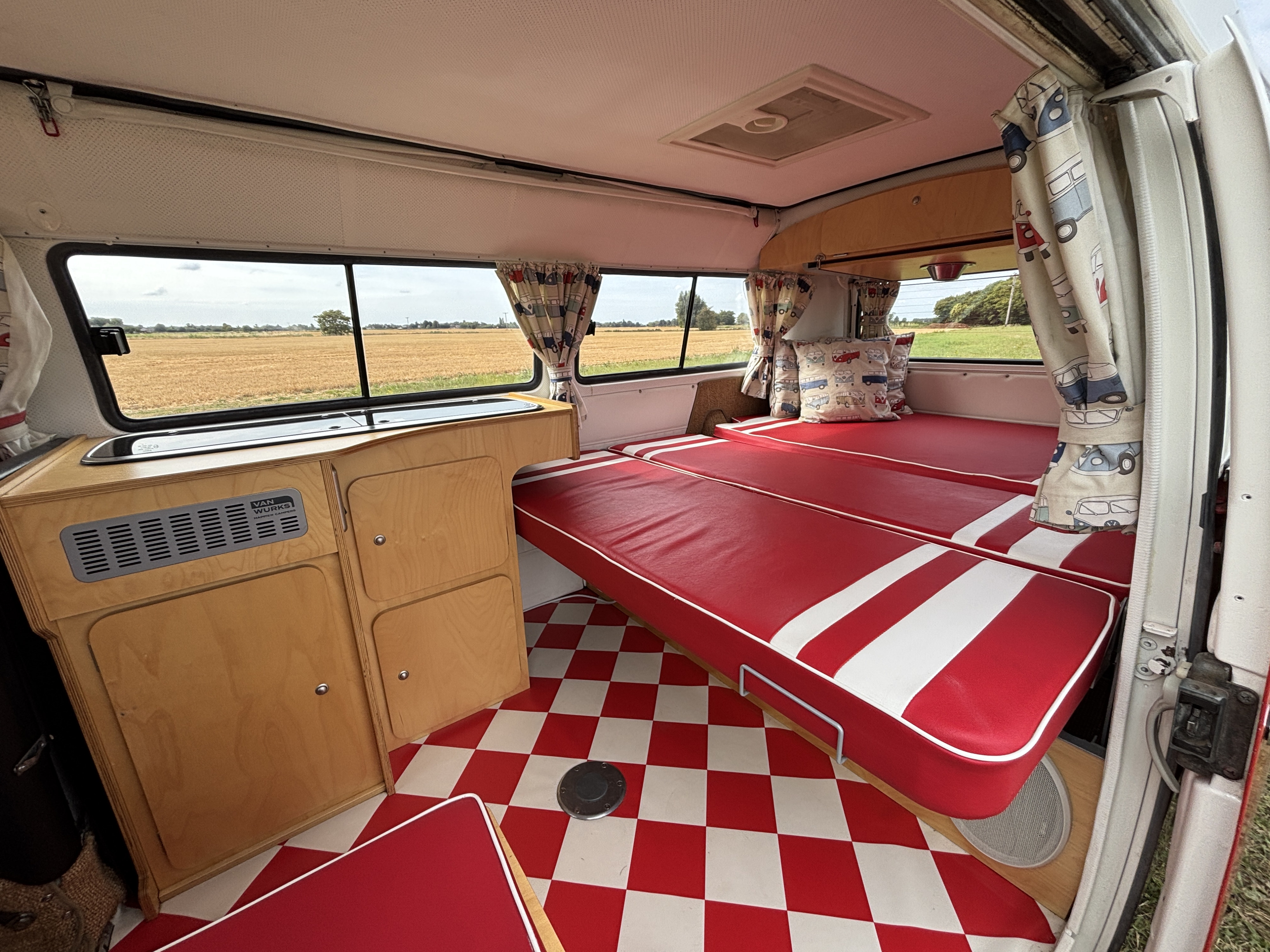 Inside a classic RV rental: red & white interior, kitchenette, comfy beds, checkered floor. Ready for road trips.. Volkswagen T2 1971