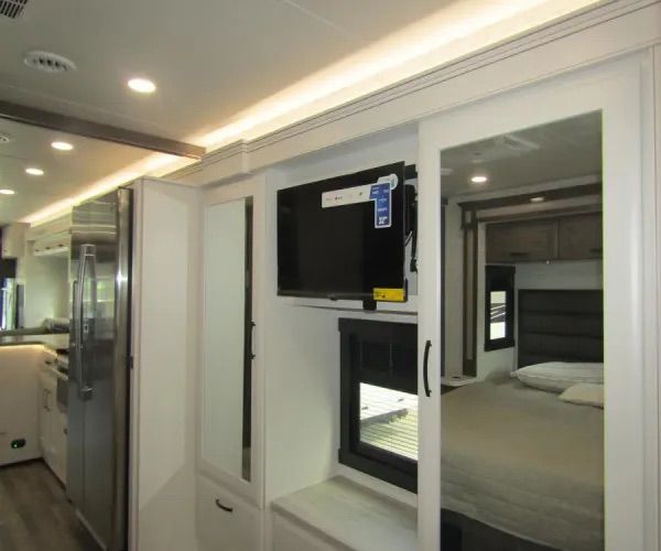 This RV rental features a modern interior: kitchen, mounted TV, and a comfortable bedroom visible in the reflection.. Jayco Precept 2025