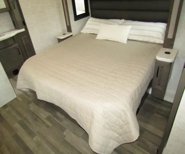 Cozy RV rental bedroom with a comfy bed, quilted bedspread, built-in nightstands, and wood-look flooring, perfect for your journey.. Jayco Precept 2025