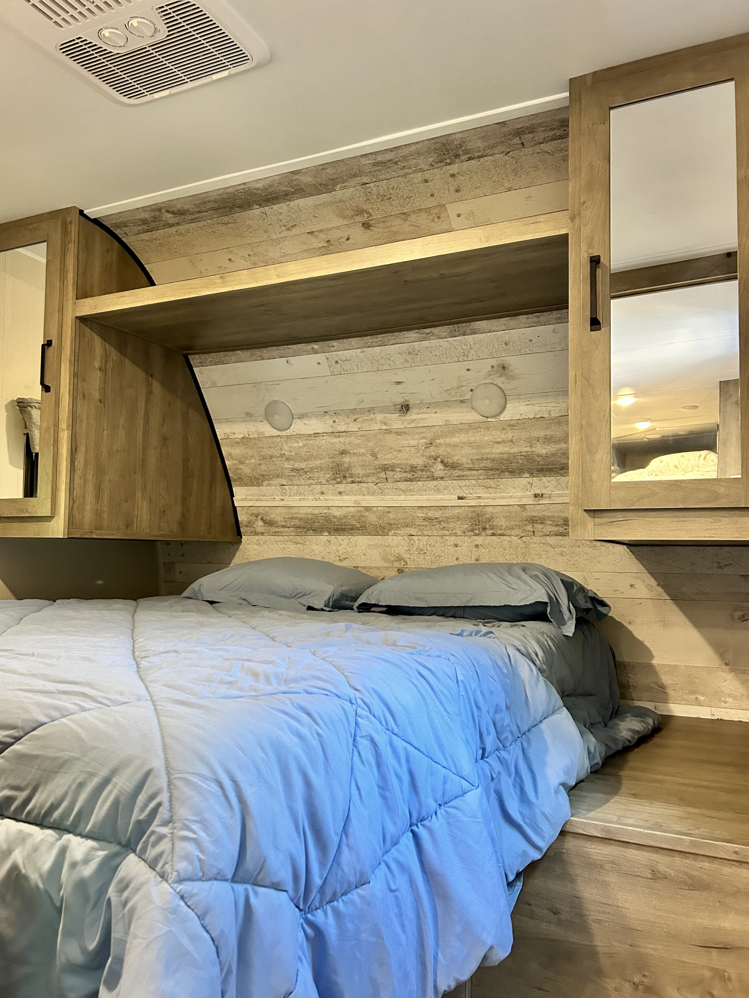 Cozy RV rental bedroom with a comfy bed, wood paneled walls, overhead storage, and AC unit. Ideal for travel.. Forest River Palomino Puma XLE 2023