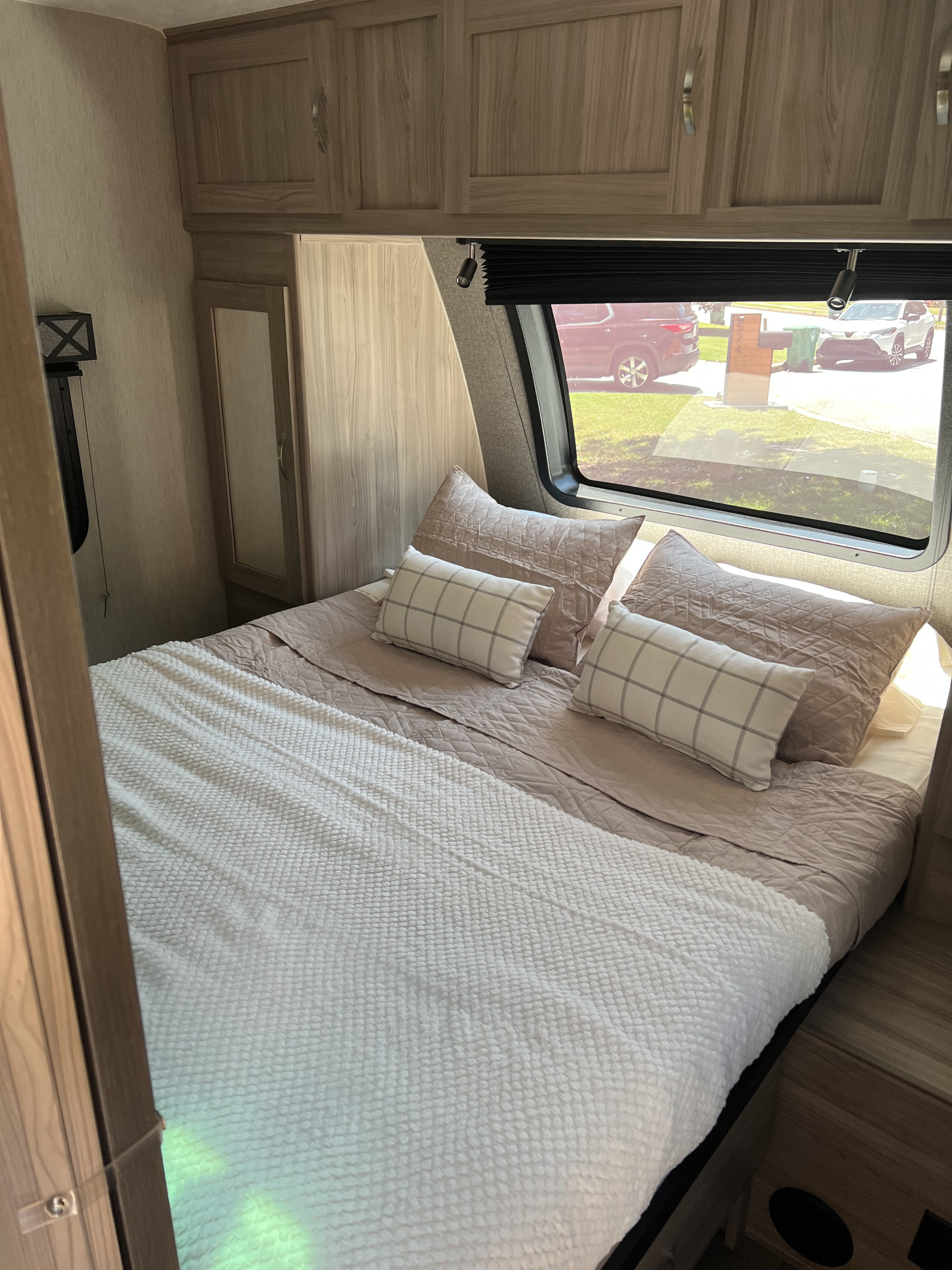 Cozy RV rental bedroom with comfortable bed, overhead storage, and window view of the outside street.. Coachmen FREEDOM EXPRESS 2021