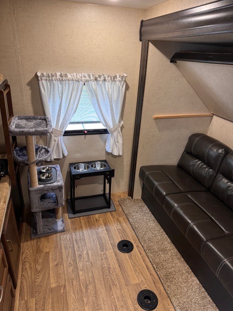 Cozy pet-friendly RV rental interior: living space with couch, cat tree, pet bowls, and wood-look flooring.. Sport Trek Sport Trek Trailer 2018