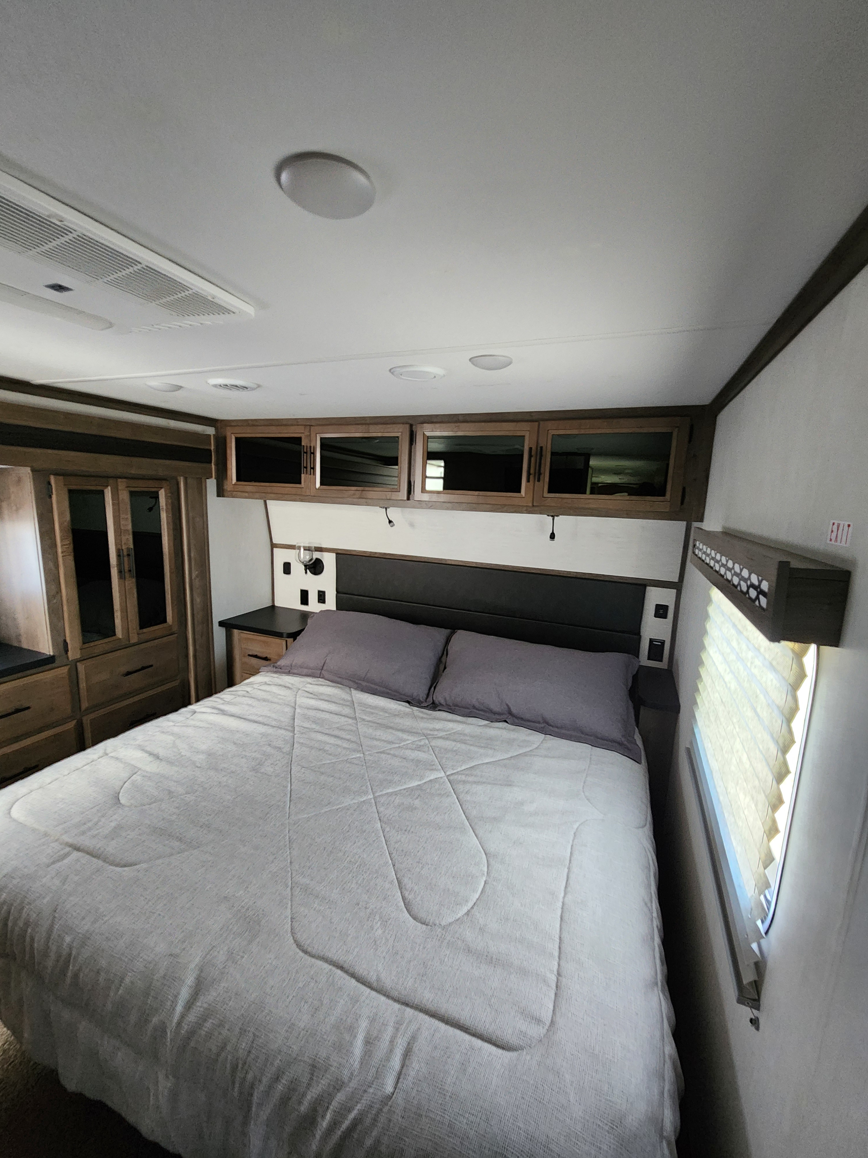 Modern RV rental bedroom featuring a comfy bed, overhead cabinets, and built-in storage, ensuring travel comfort.. Forest River Vengeance Vengeance Rogue Amored Toy Hauler 2022