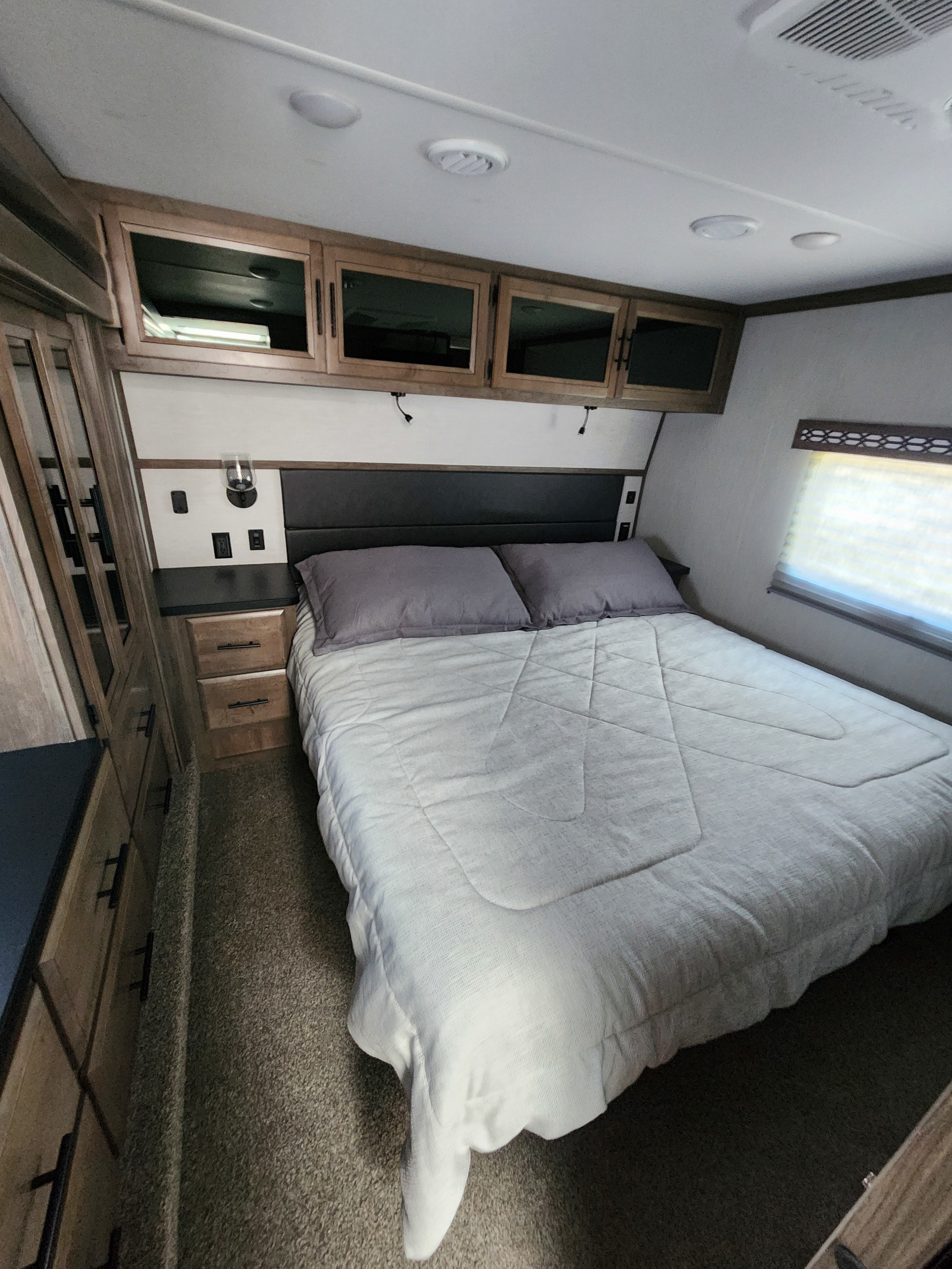 Comfortable RV rental bedroom featuring a full bed, overhead cabinets, and built-in storage. Ideal for travel.. Forest River Vengeance Vengeance Rogue Amored Toy Hauler 2022