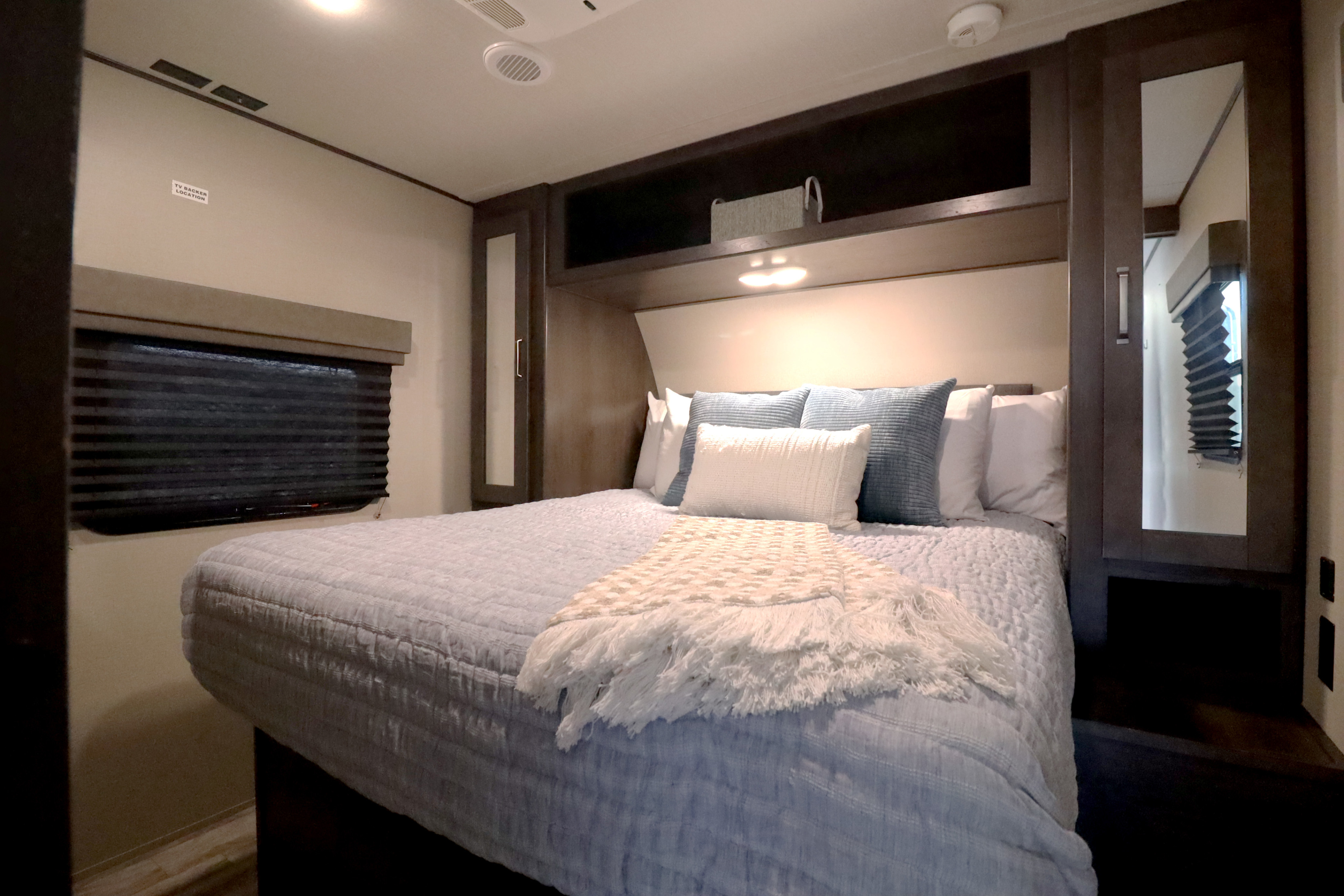 Cozy RV rental bedroom with a comfortable bed, window, overhead storage, and TV prep. Perfect for your next adventure!. Grand Design Transcend Xplor 2022