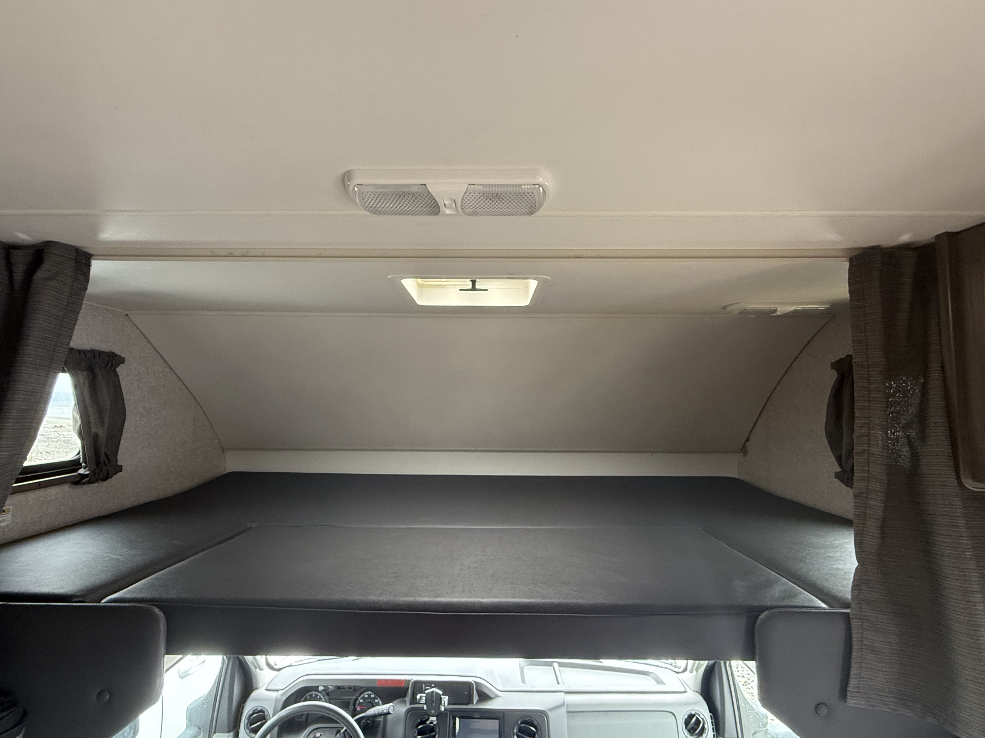 RV rental: Spacious cab-over bunk bed with side windows, curtains, and dashboard view below.. Winnebago Minnie Winnie 2020