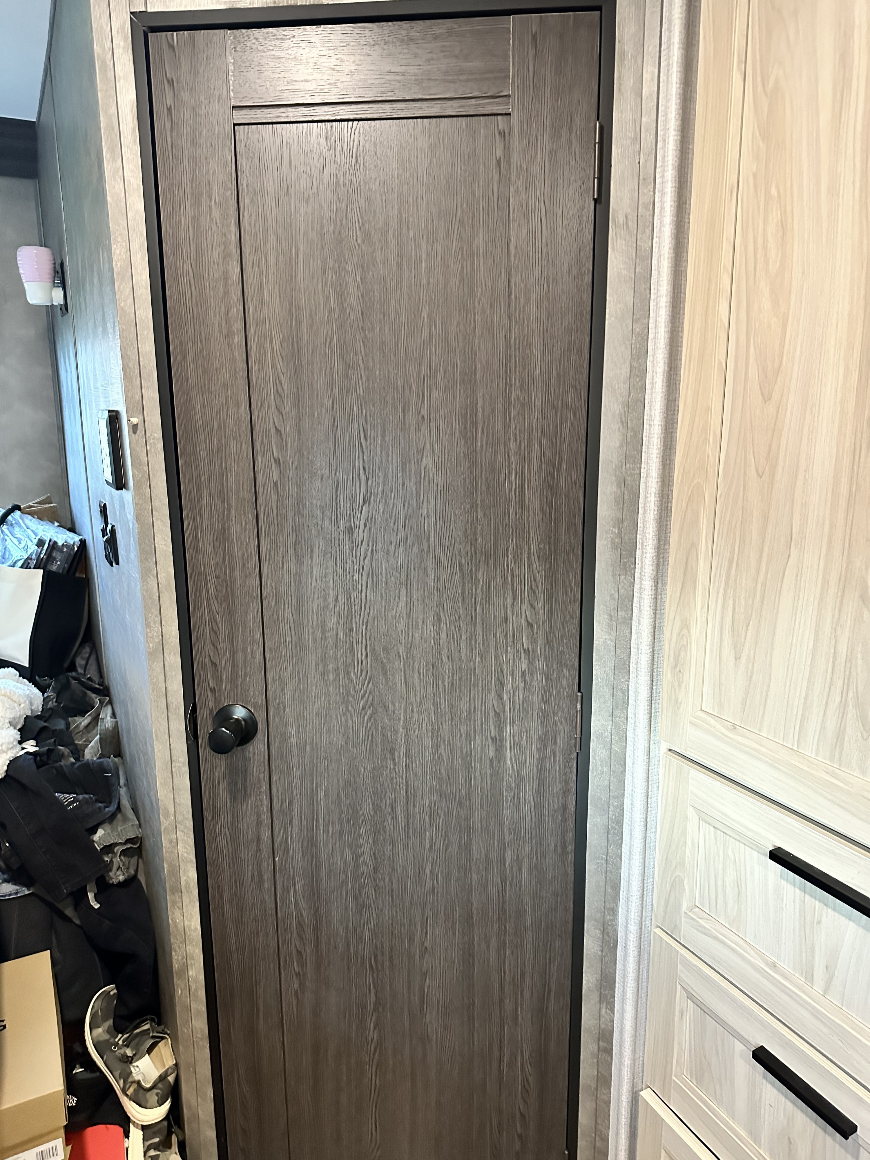 Inside an RV rental: a dark wood grain door with black doorknob, next to light wood-look cabinets.. Forest River 2551 dsle 2021