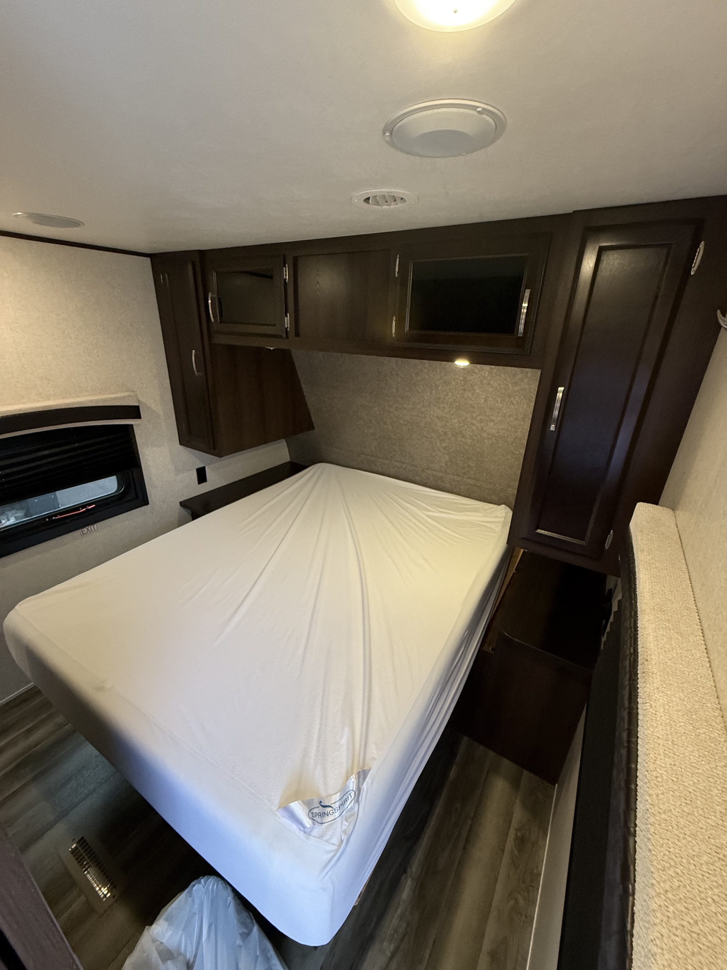 Compact RV rental bedroom with a bed, overhead cabinets, and window, perfect for travel.. Jayco Jay Flight 2020