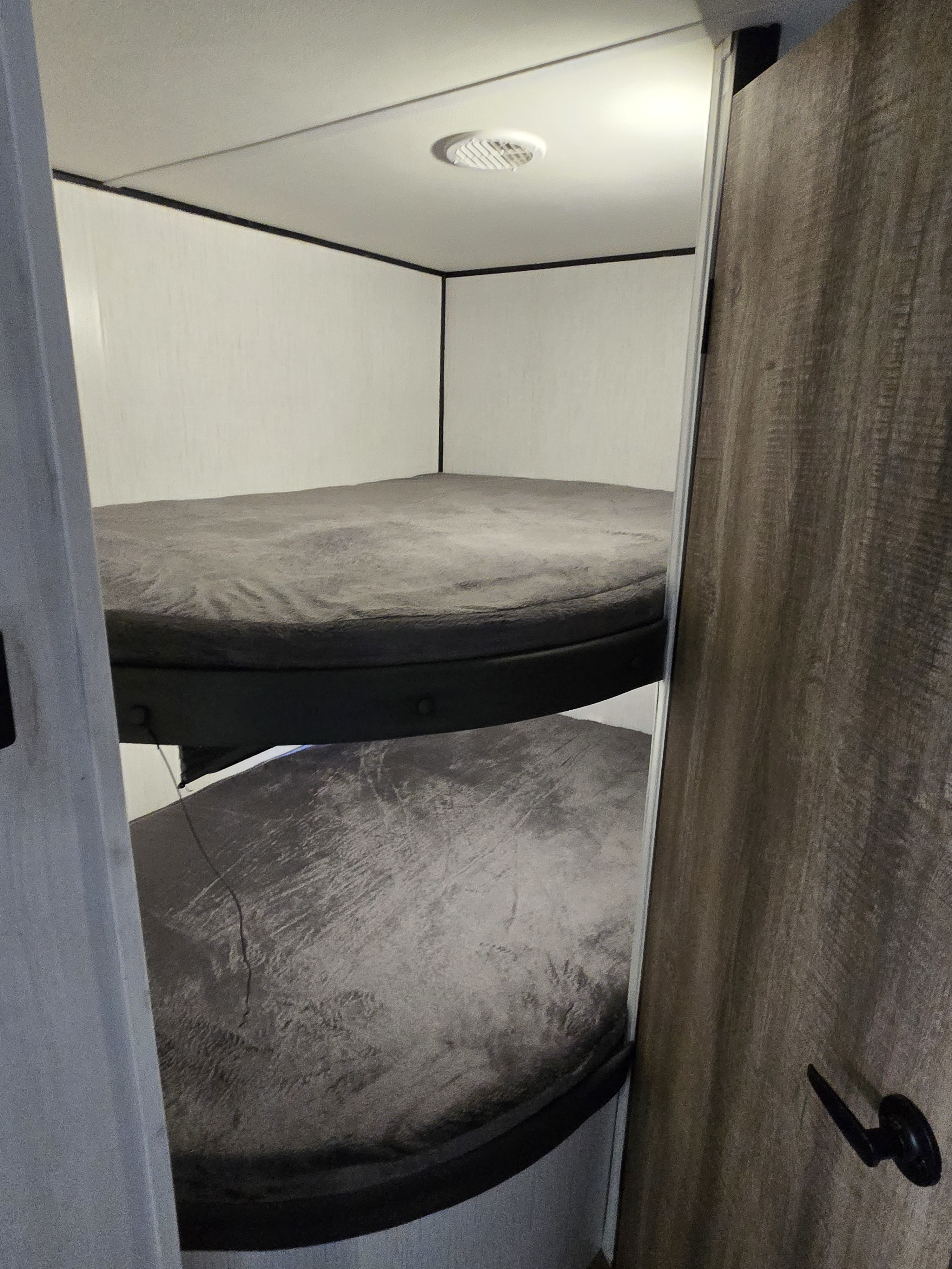 Inside an RV rental: view of two cozy bunk beds with light walls and ceiling vent. Perfect for family trips.. Heartland RVs Trail Runner 2022