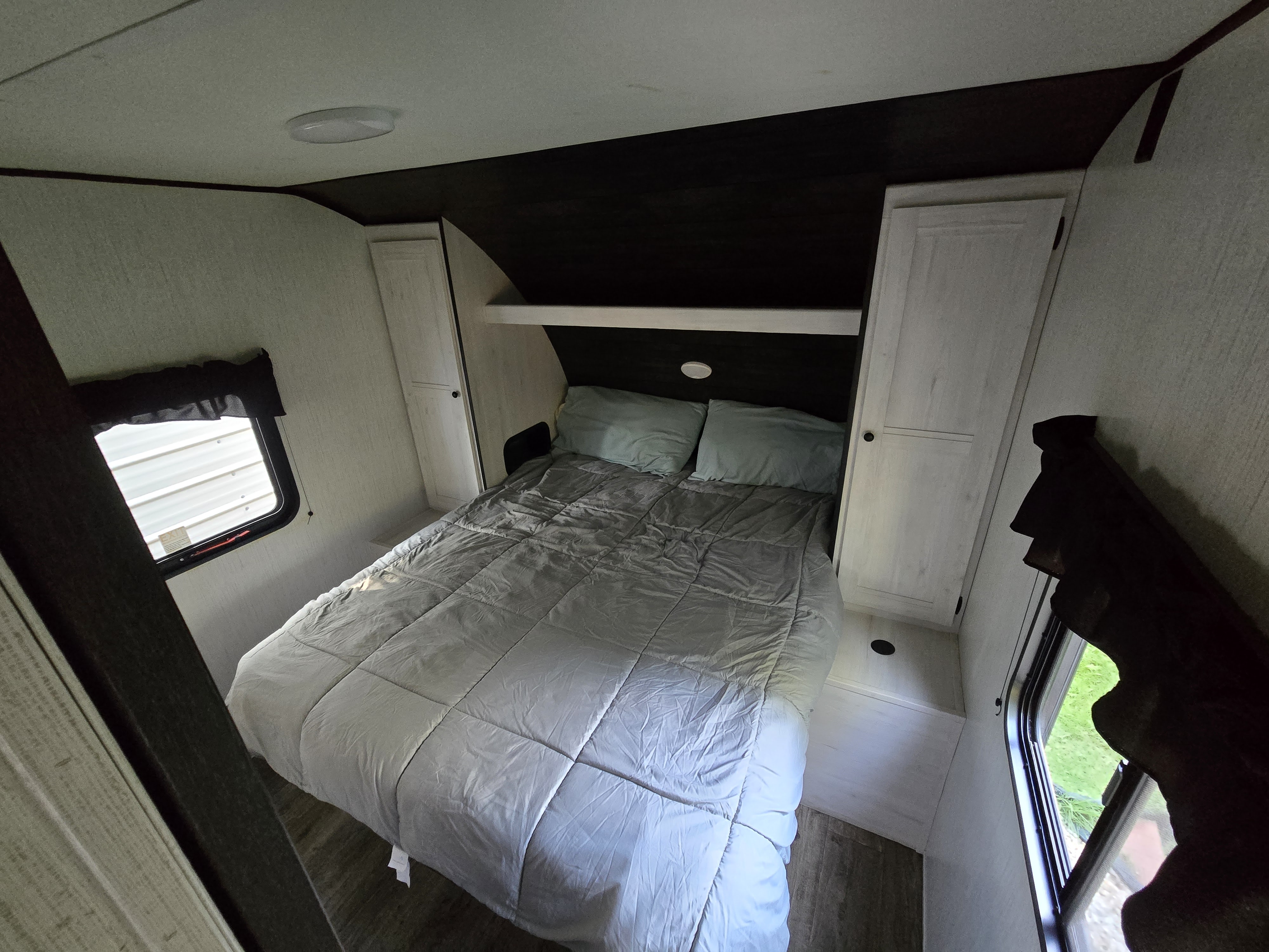 Cozy RV rental bedroom with a comfortable bed, built-in storage, and bright windows, perfect for your next adventure.. Heartland RVs Trail Runner 2022