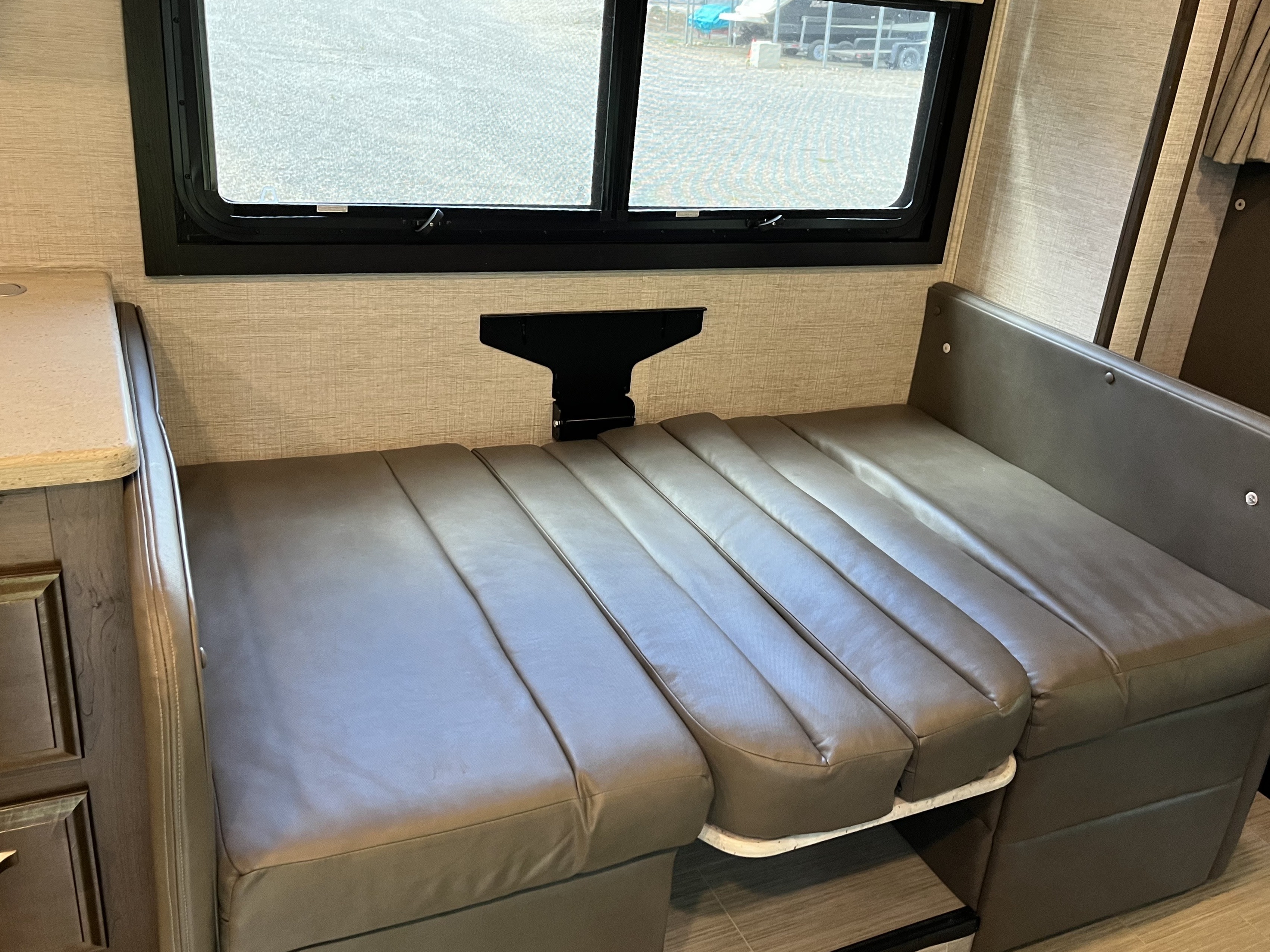 RV rental dinette converted to a bed with comfortable cushions and a large window, offering a cozy interior space.. Entegra Coach Esteem 2021