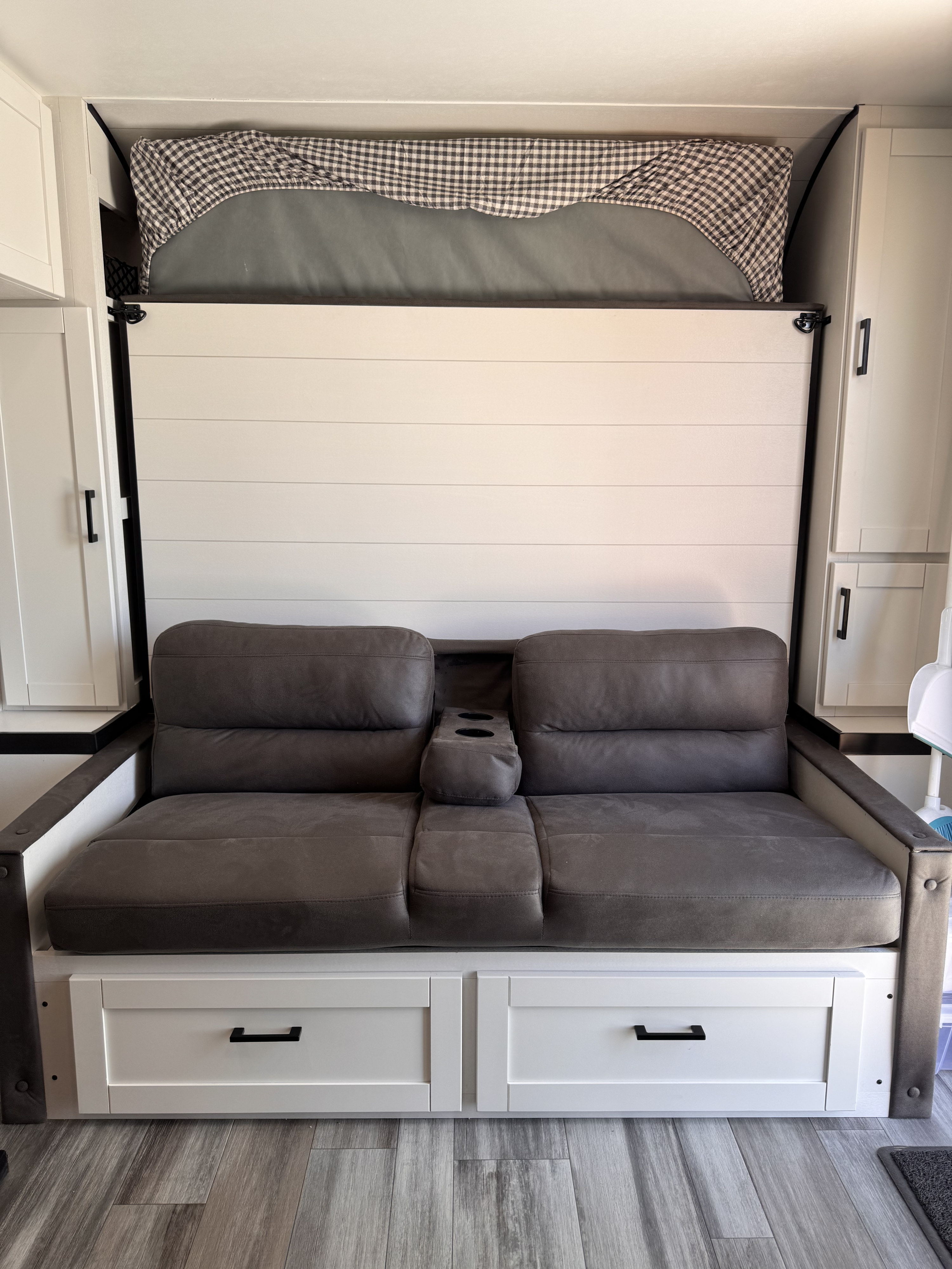 Modern RV rental interior with convertible sofa, under-seat storage drawers, and a neatly stowed Murphy bed.. Jayco Jay Flight 2026