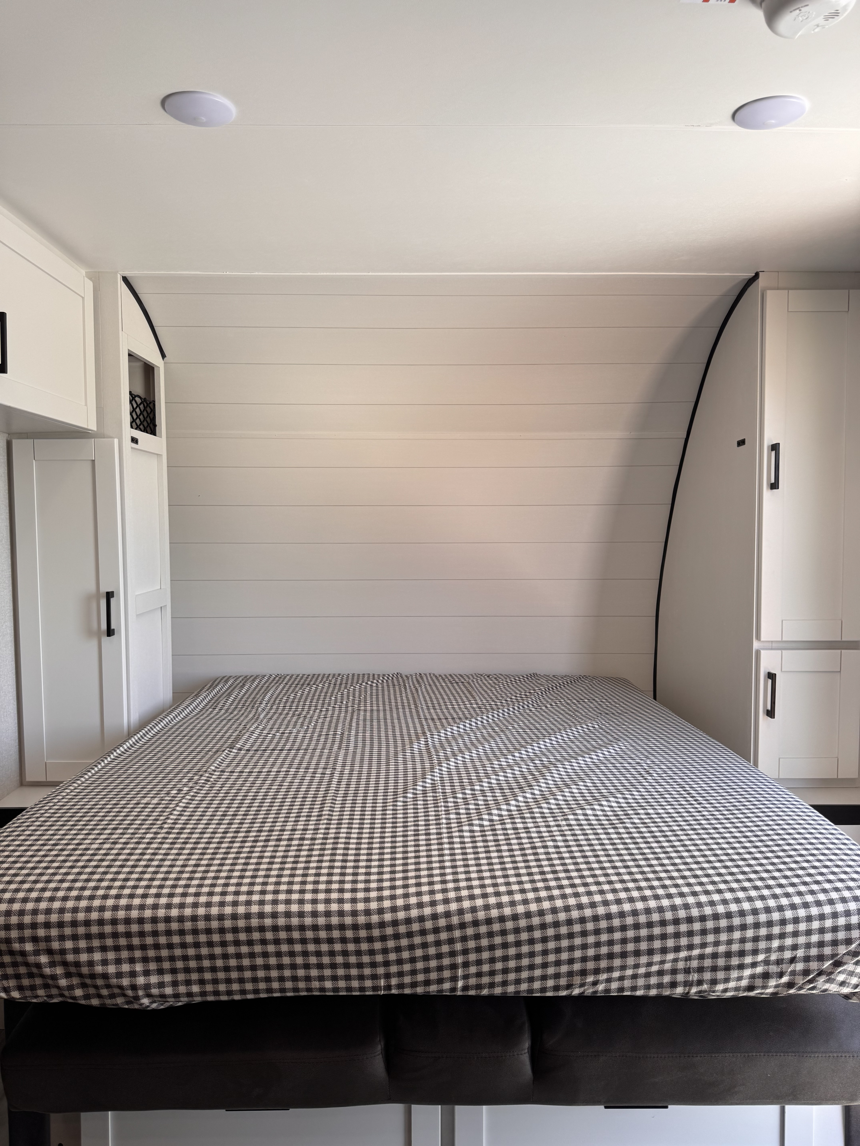 Cozy RV rental bedroom featuring white shiplap walls, built-in storage, and a black and white checkered bed.. Jayco Jay Flight 2026