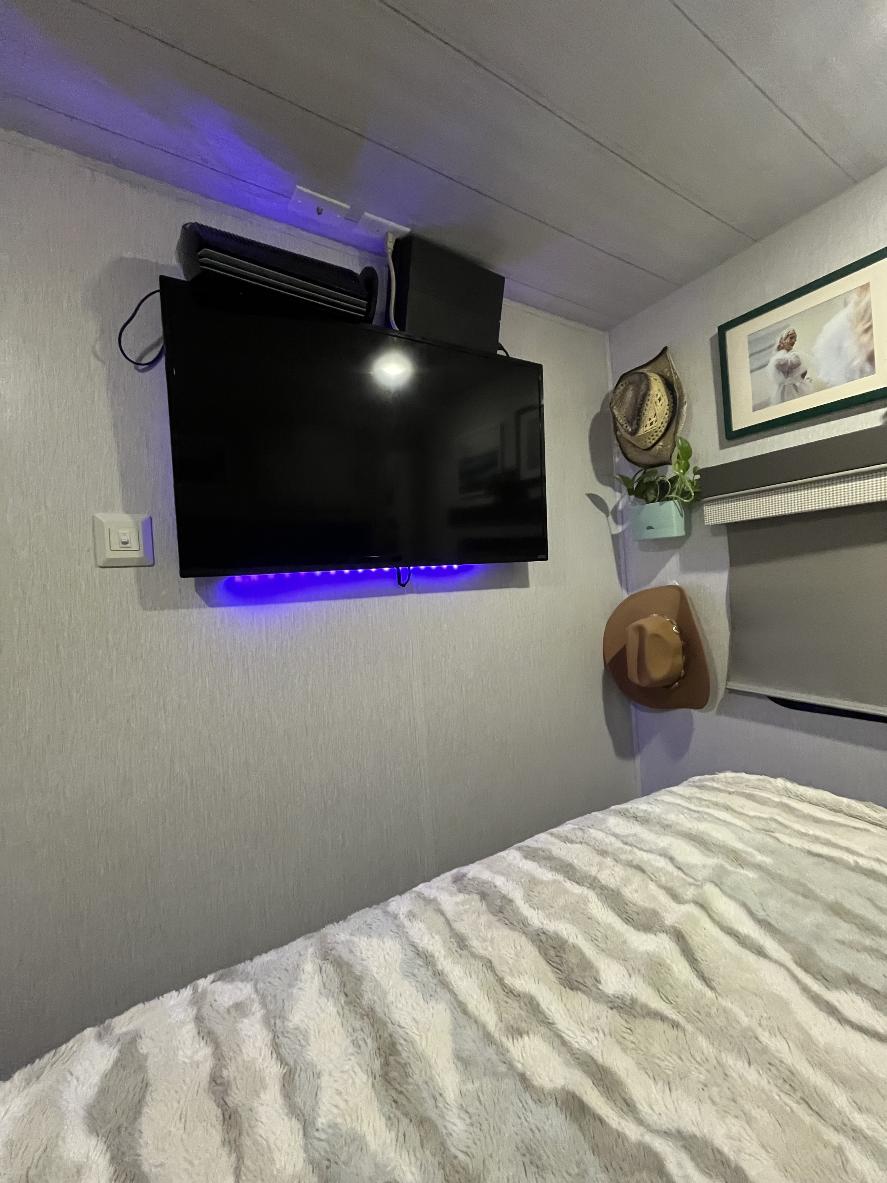 RV rental bedroom interior: Wall-mounted TV with blue LEDs, personal decor, and cozy textured bed.. Salem Forest River 2023