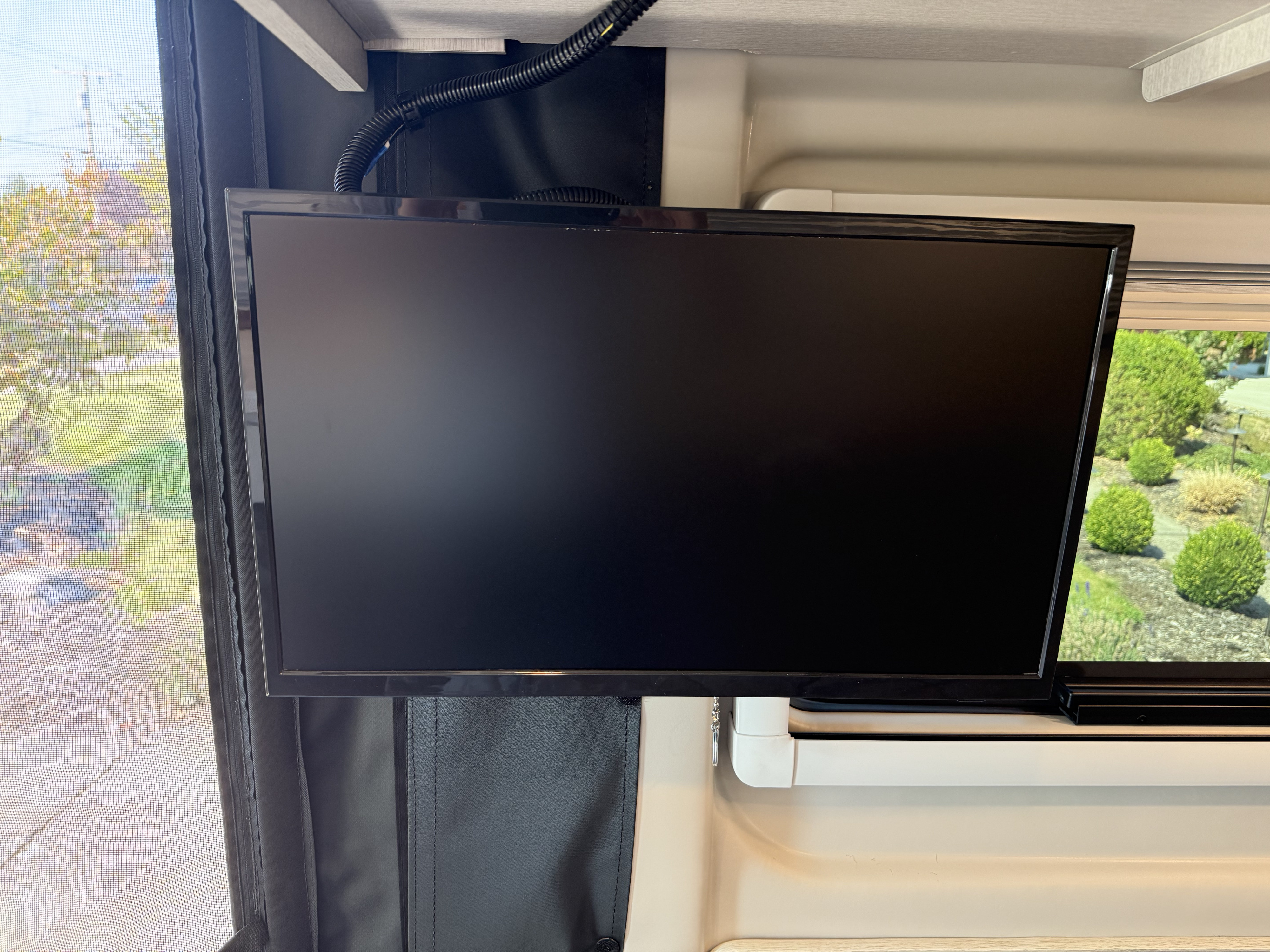 RV rental interior featuring a mounted TV next to a window with a screen, showcasing an outdoor view.. Thor Tellaro 2026