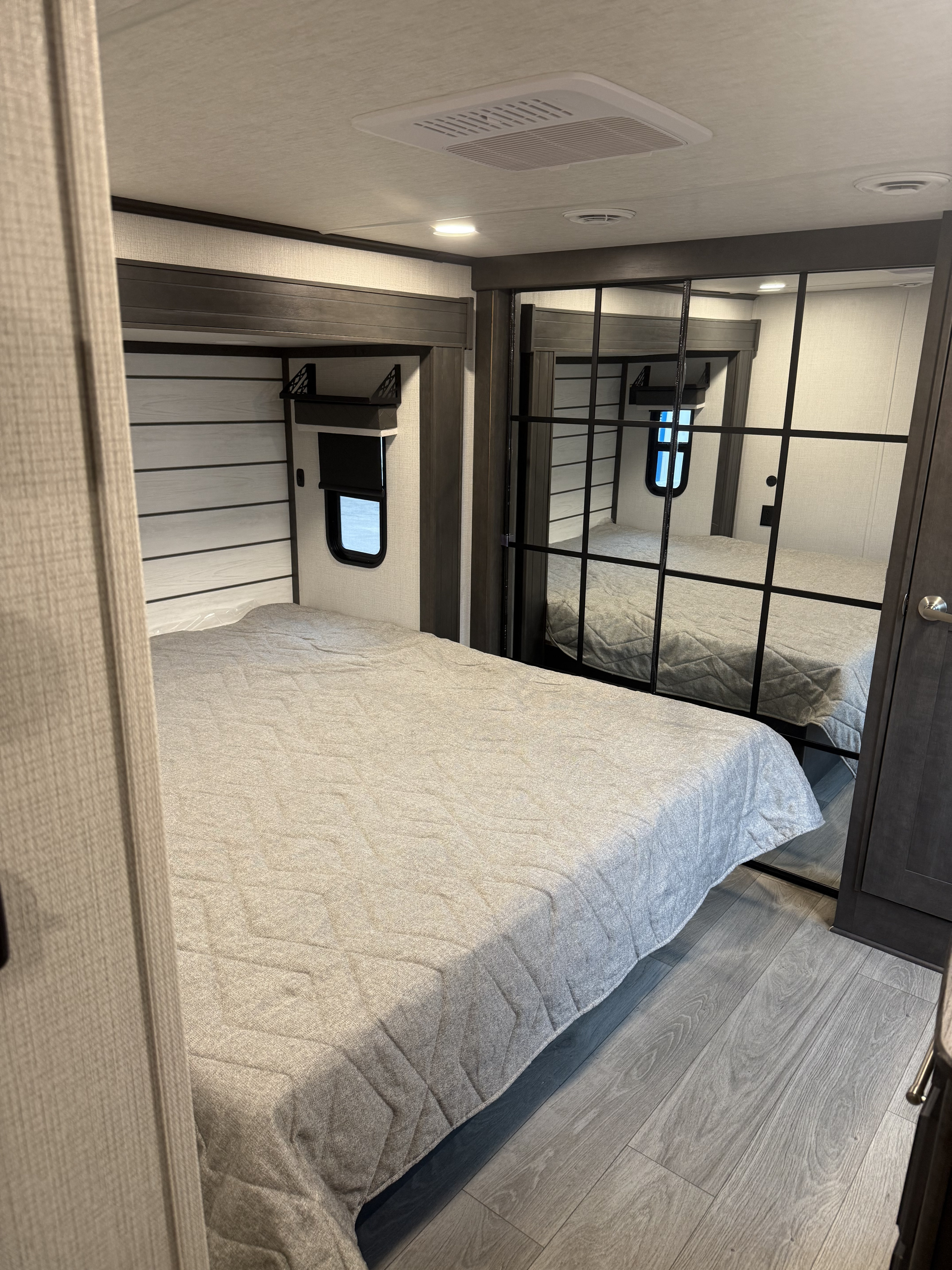 Modern RV rental bedroom with queen bed, mirrored closet, and AC for a comfortable stay.. Keystone Cougar 2025