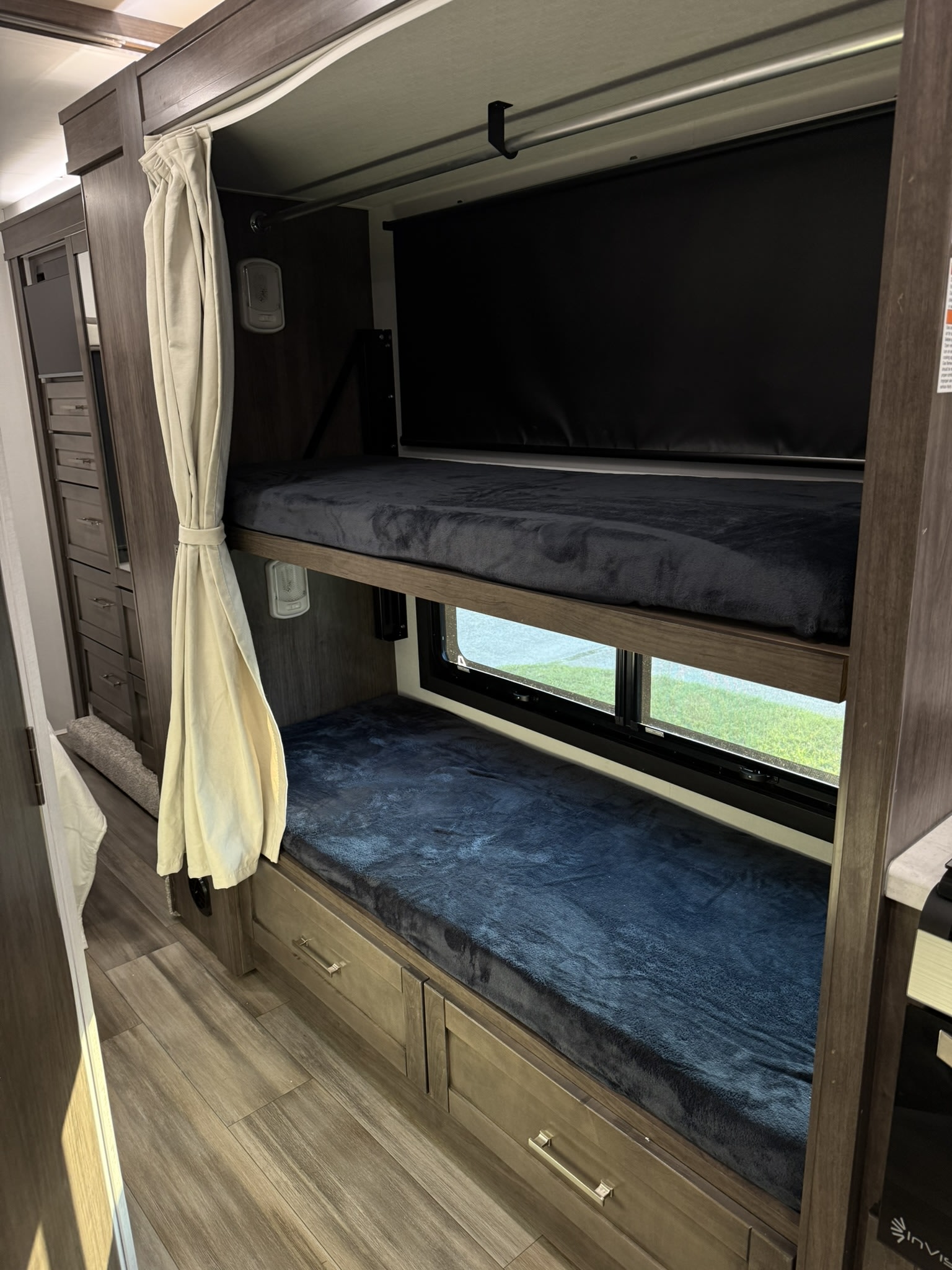 Inside an RV rental: two comfy bunk beds with dark blankets, individual lights, and a window view, offering a great camping sleep solution.. Entegra Coach Esteem 2026