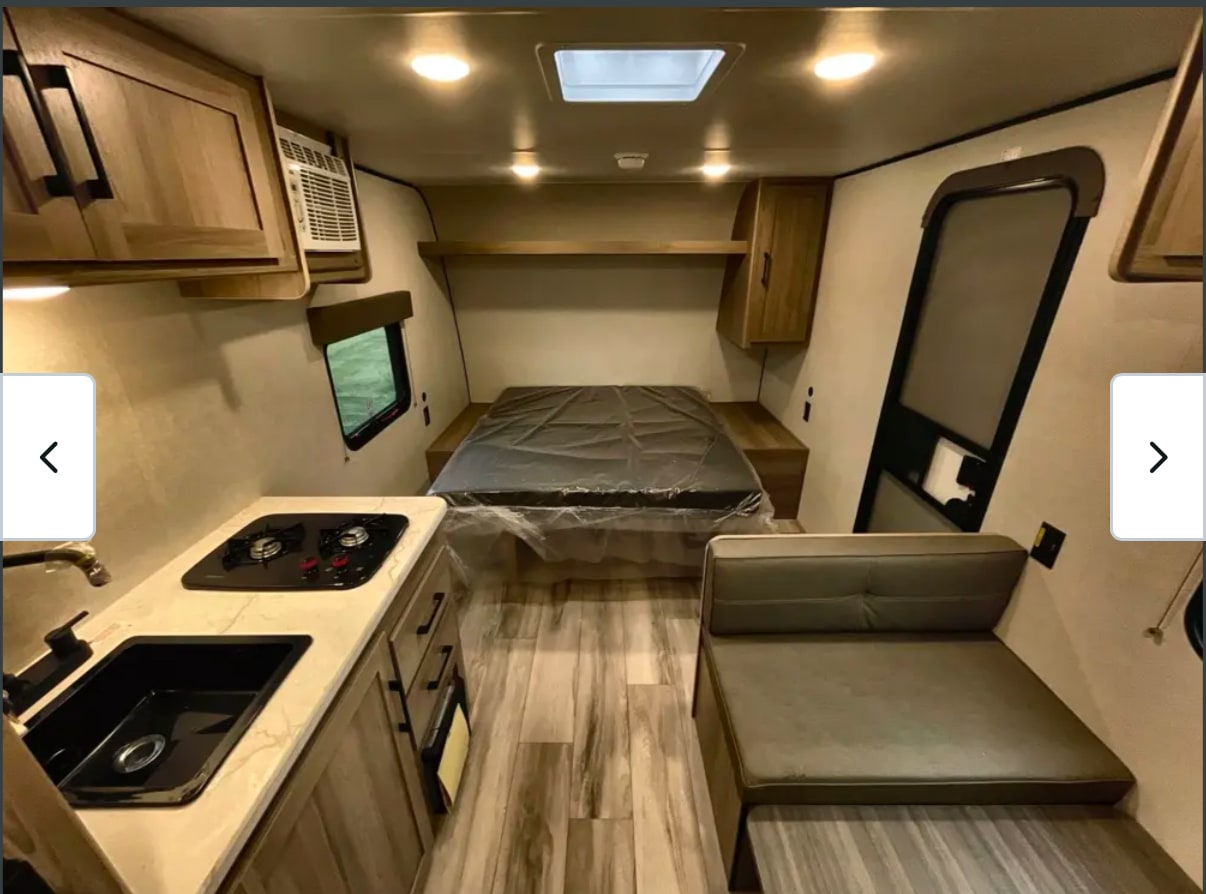Explore this cozy rv rental interior, featuring a compact kitchen, bed, and dinette for comfortable travel.. Keystone Coleman 2025