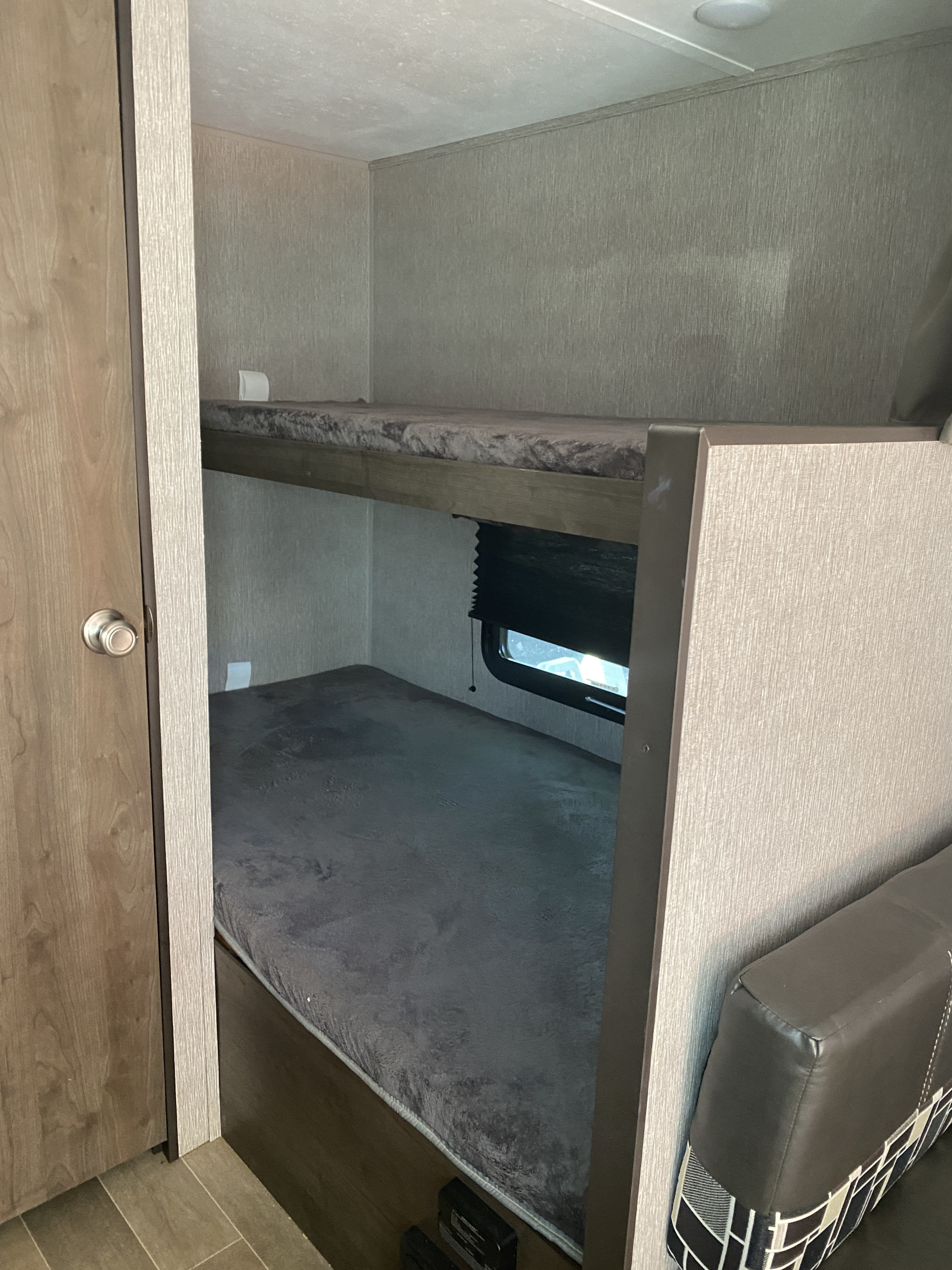 This RV rental features stacked bunk beds with soft gray mattresses, a window on the lower bunk, and a cozy sleeping area.. Dutchmen Coleman Lantern LT 2020