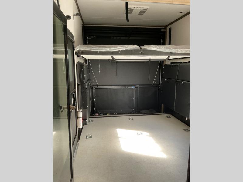 This RV rental toy hauler features a versatile cargo space with a raised lift bed and floor tie-downs, ready for adventure.. Forest River Vengence 2024