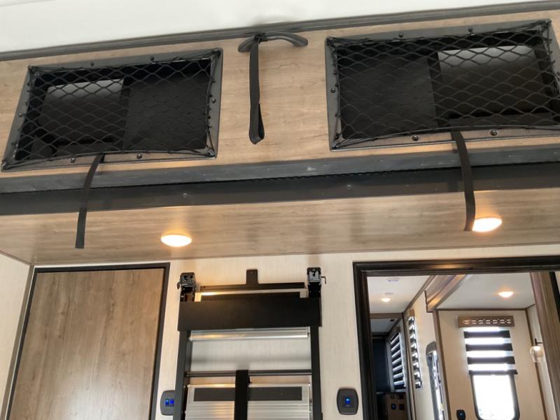 Functional RV rental interior: overhead netted storage, bright lighting, and wood paneling for a modern travel experience.. Forest River Vengence 2024