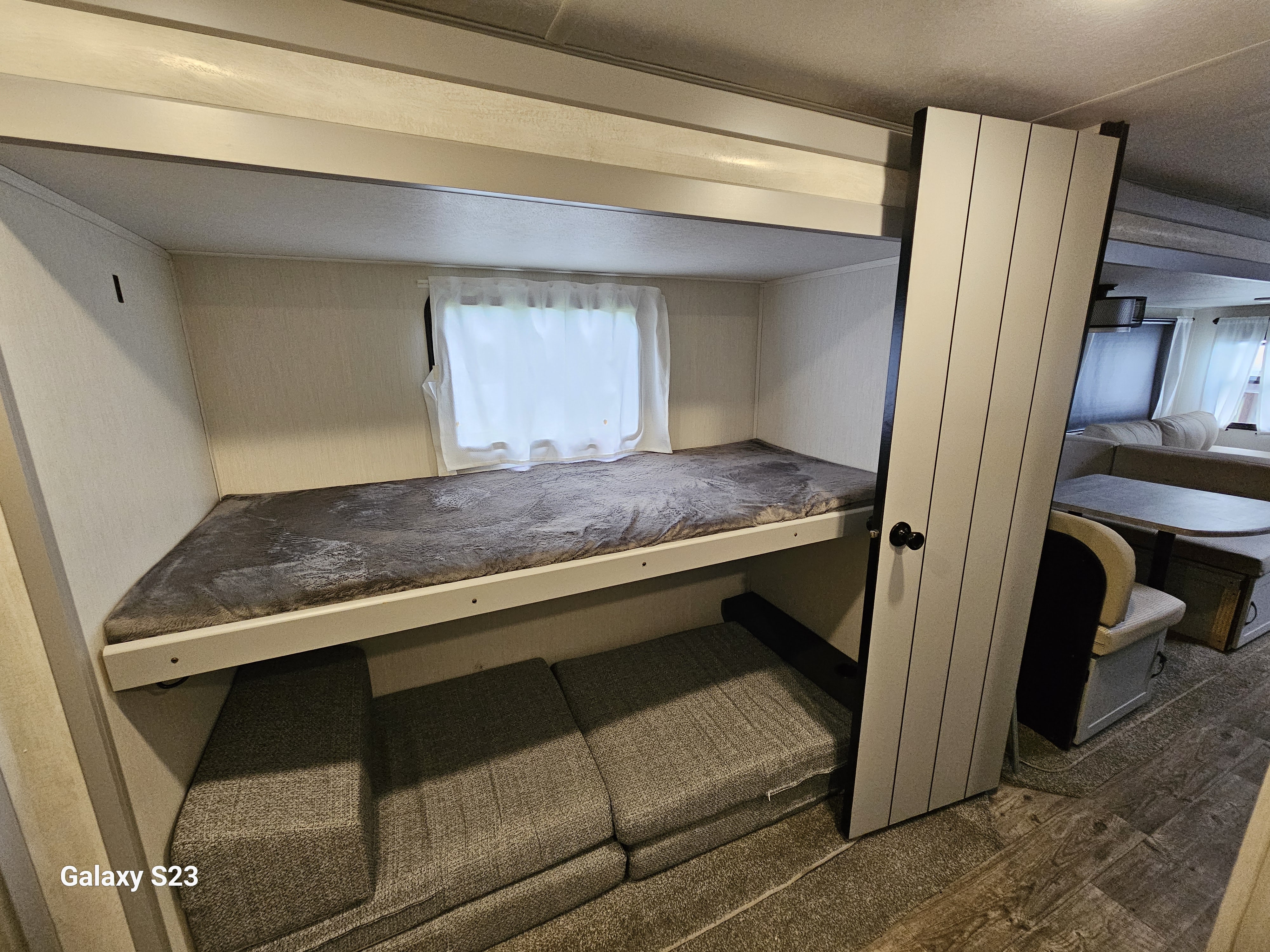 Cozy RV rental bunkhouse: features an upper bunk and adaptable lower sofa seating, maximizing compact living space.. Forest River Vibe 2023