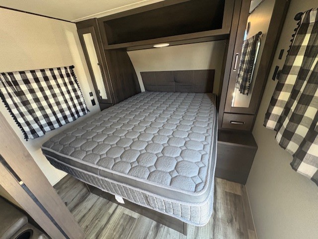 RV rental bedroom: a grey mattress, overhead storage, and black & white plaid curtains, ready for your trip.. Grand Design Transcend Xplor 2022