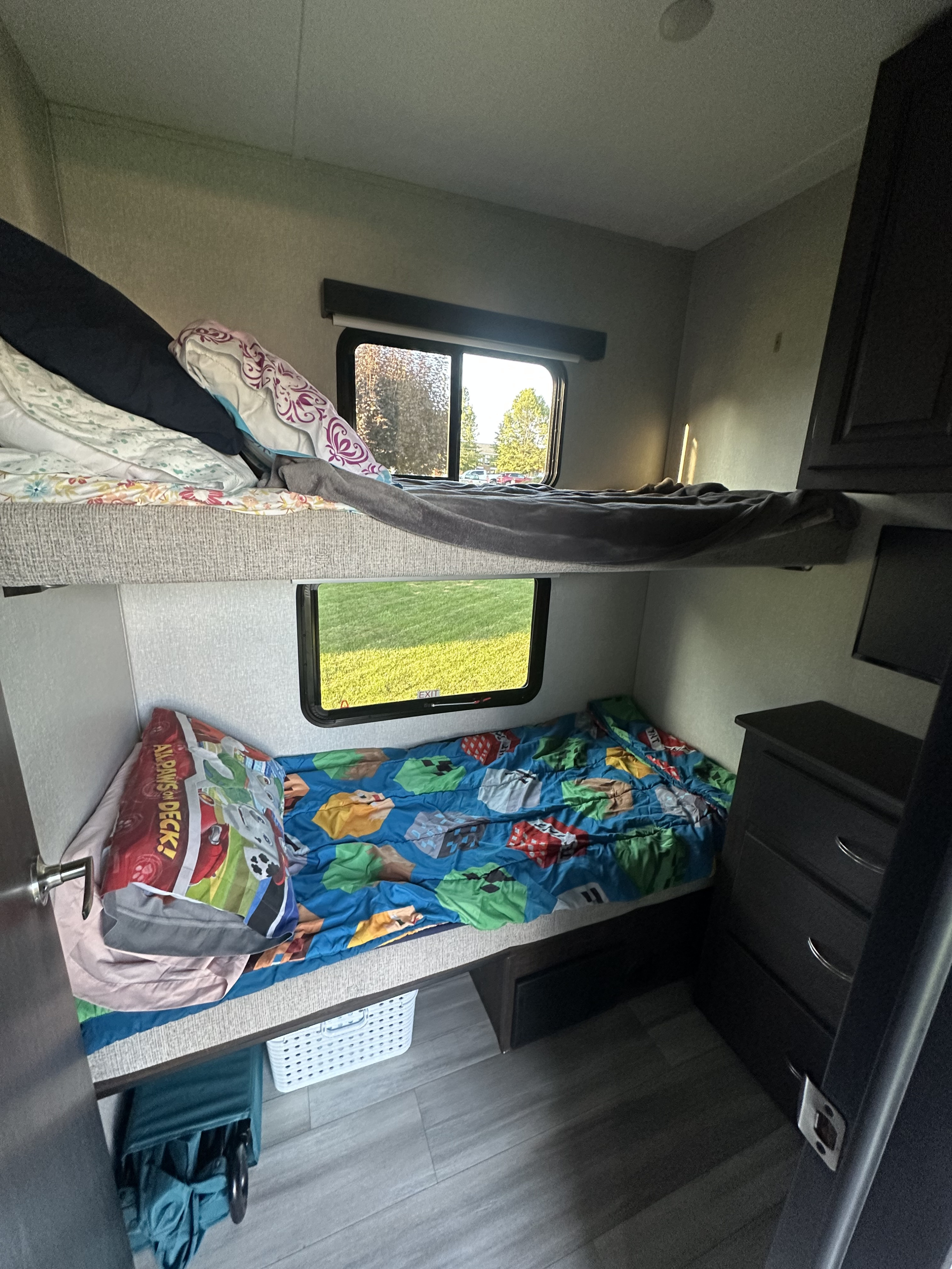 Cozy bunk beds for kids in an RV rental, featuring colorful bedding (Minecraft & Paw Patrol) and bright windows.. Shasta Phoenix 30BH 2022