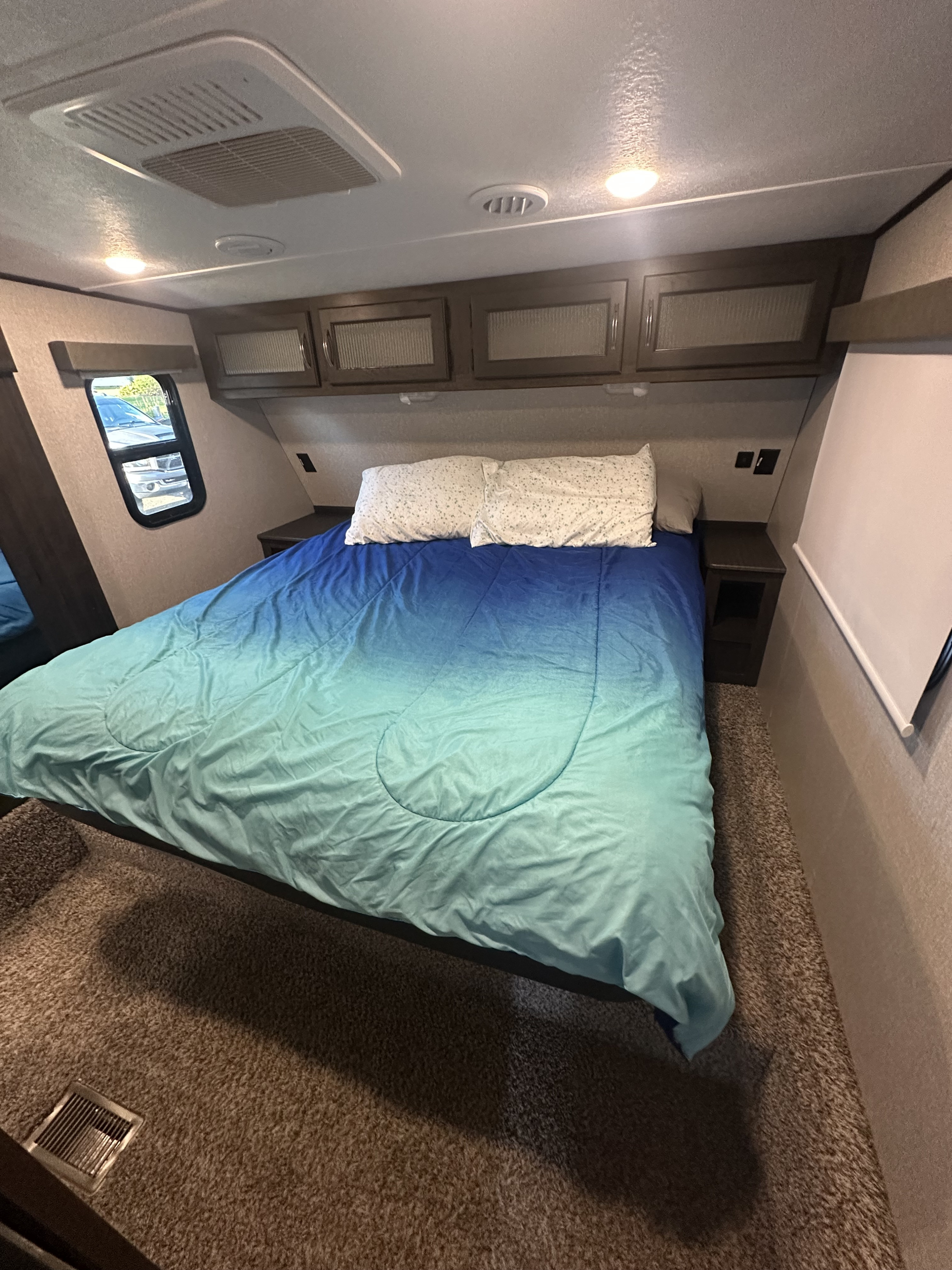 Comfortable RV rental bedroom featuring an ombre bed, overhead cabinets, window, and AC. Ideal for travel.. Shasta Phoenix 30BH 2022