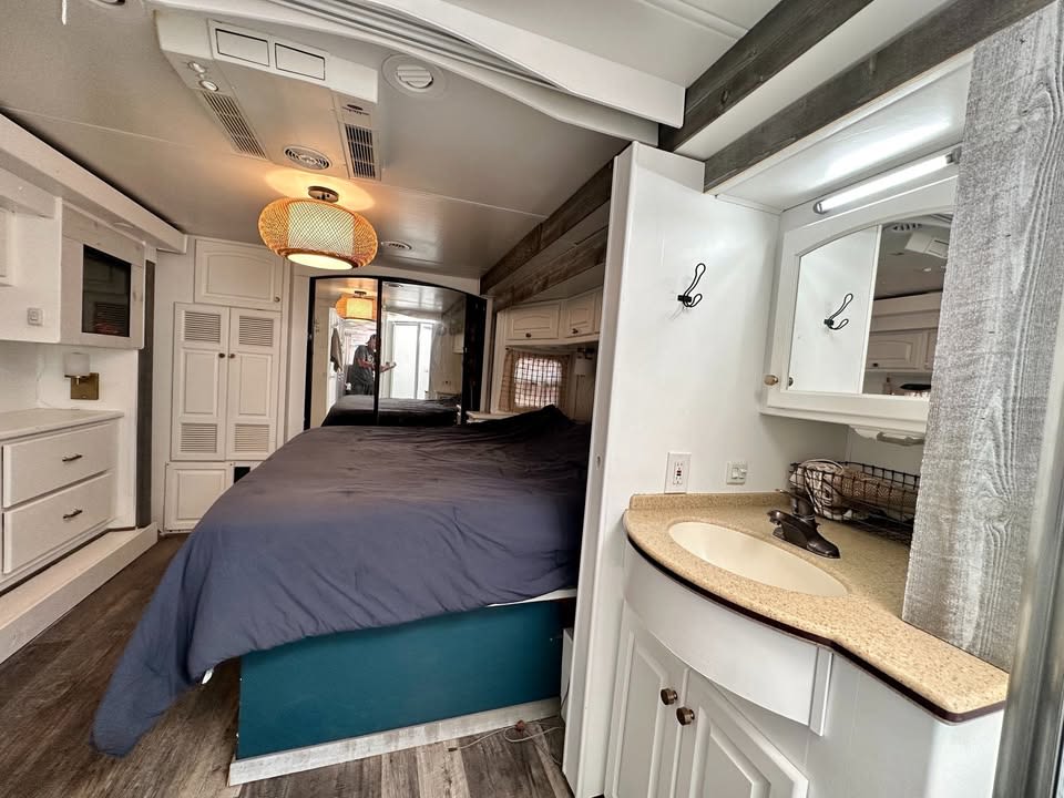 Spacious RV rental interior featuring a bright bedroom with a large bed, modern fixtures, and a vanity area with a sink.. Damon Corporation Tuscany 2008