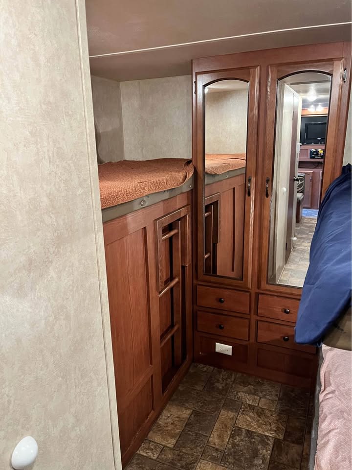 Compact RV rental bunk beds with integrated storage and mirrored doors, showcasing efficient interior design.. Forest River Wildwood X-Lite 2013