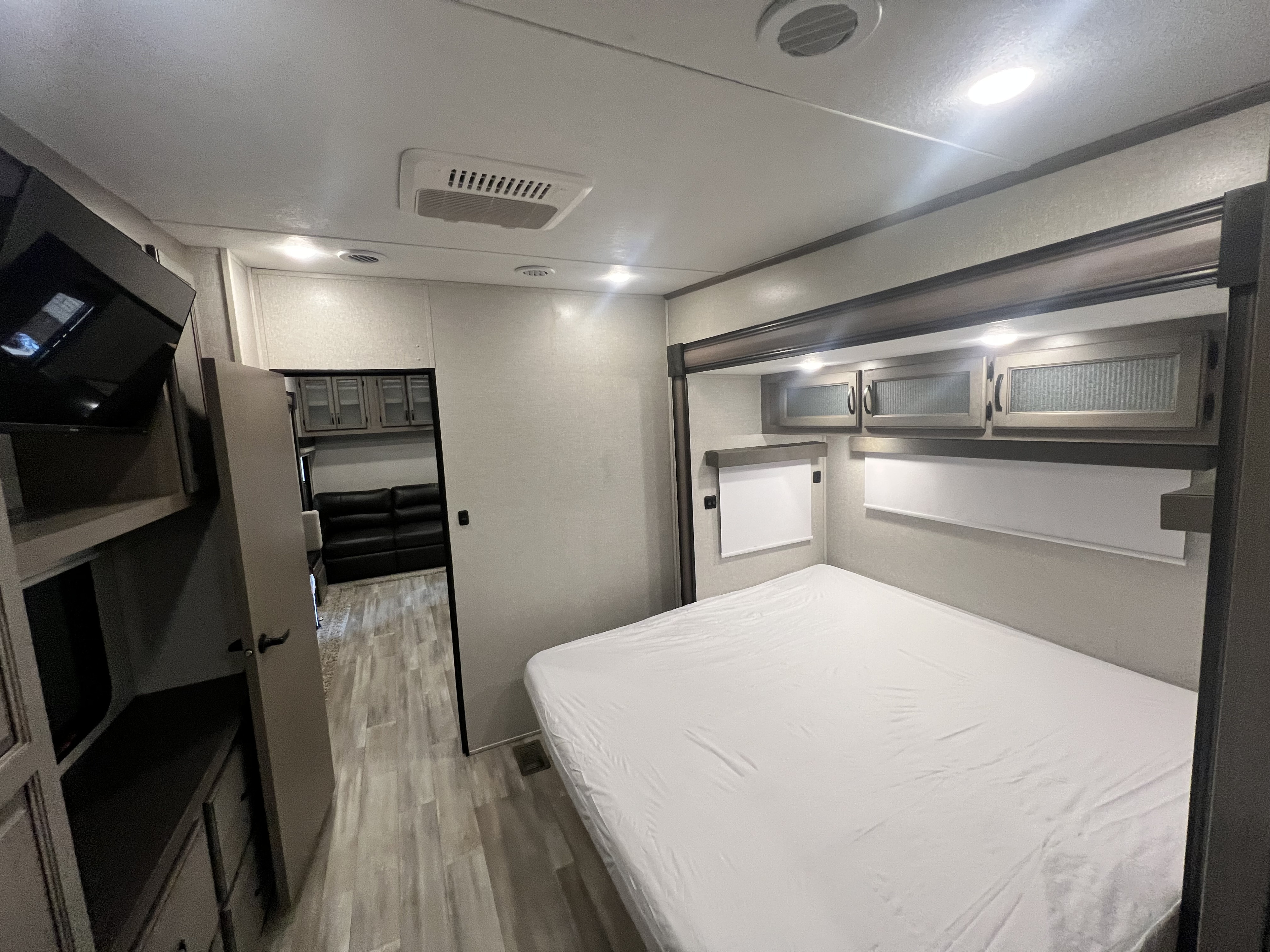 Explore this comfortable RV rental bedroom interior, featuring a spacious bed, overhead storage, and built-in TV.. Forest River Coachman Chaparral 2022
