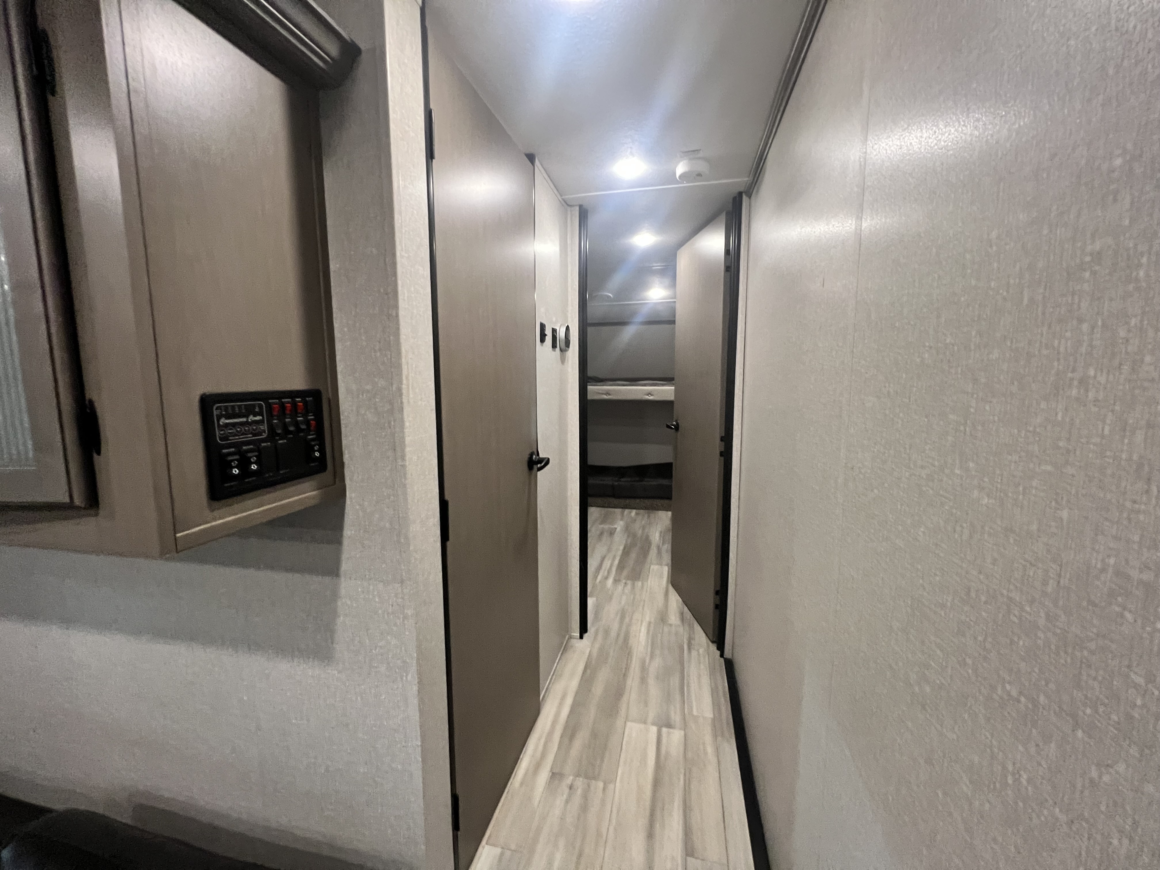 RV rental interior: A well-lit hallway featuring a control panel, multiple doors, and bunk beds visible at the end.. Forest River Coachman Chaparral 2022