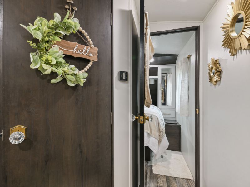 Discover this modern RV rental bedroom & hall with chic decor like sunburst mirrors & a "hello" wreath.. Keystone RV Bullet Premier Ultra 2020